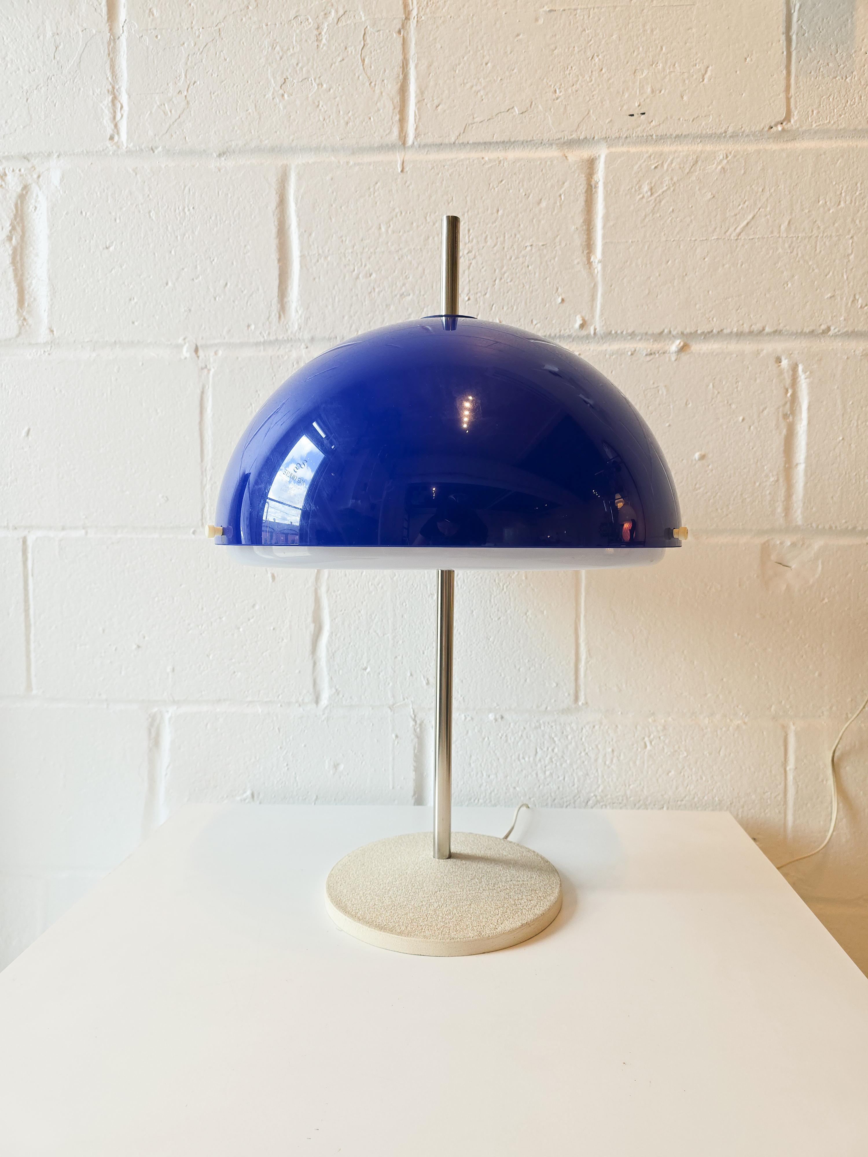 Lampada da tavolo con paralume in acrilico in stile Space Age. Il paralume è composto da due pezzi e un paralume acrilico bianco si trova nella parte inferiore del paralume superiore blu scuro arrotondato. La forma ricorda quella di un fungo. In
