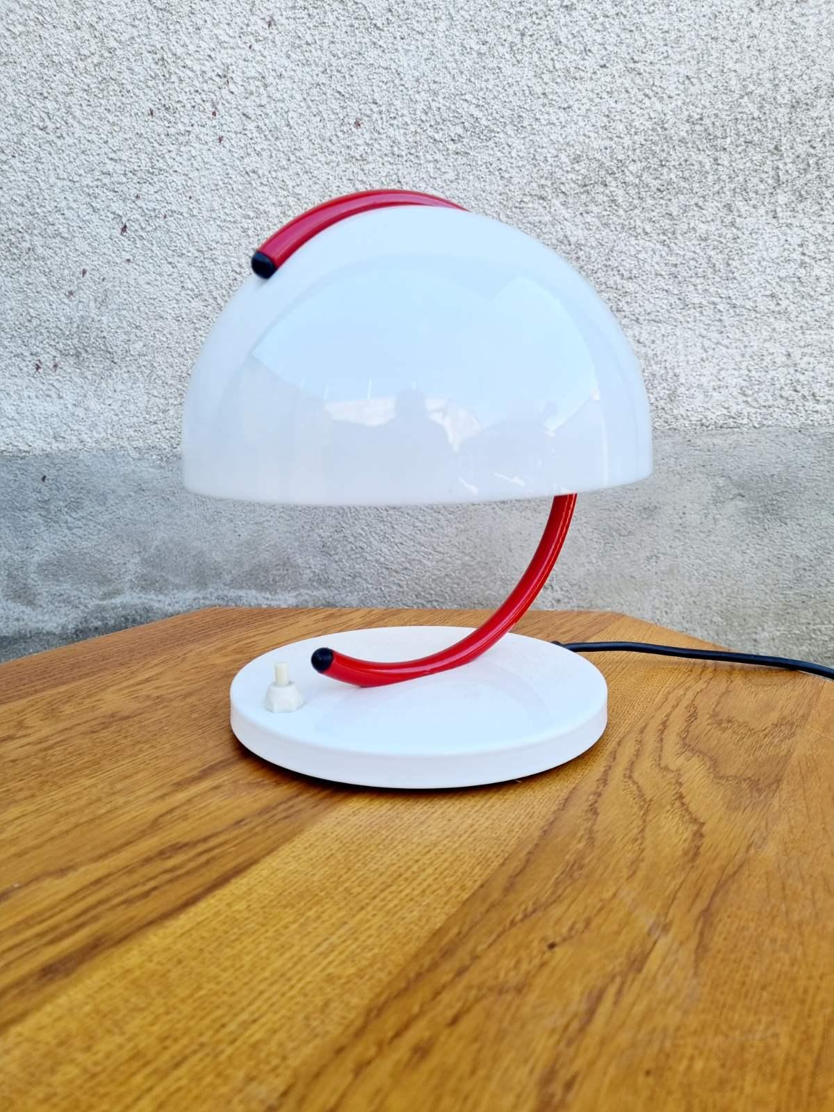 Table lamp designed by Luigi Massoni for iGuzzini in thelate 60s and produced by Meblo, Yugoslavia.  Classic Space age design
The shade is made of white plastic that is attached to a curved red rod that connects the shade to the round chrome base.
