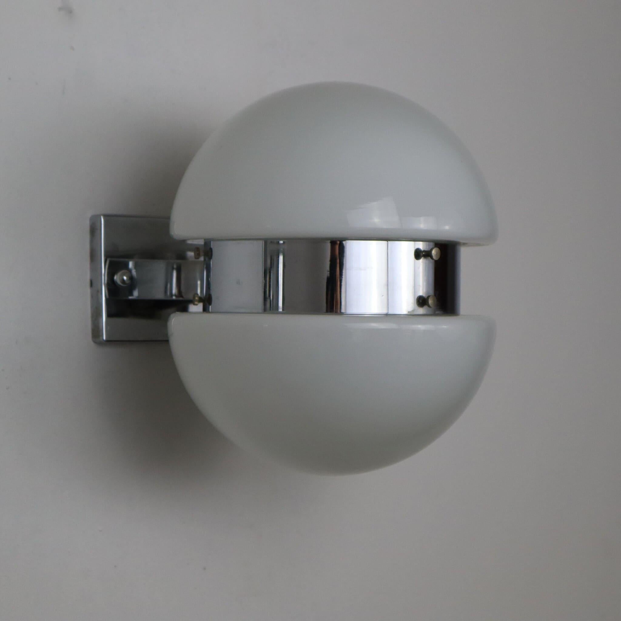 Cette élégante paire d'appliques de style NO AGE, produite en Italie dans les années 70, est un parfait exemple de design futuriste et innovant. Chaque applique est composée de deux vitres en verre opale blanc, qui émettent une lumière douce et
