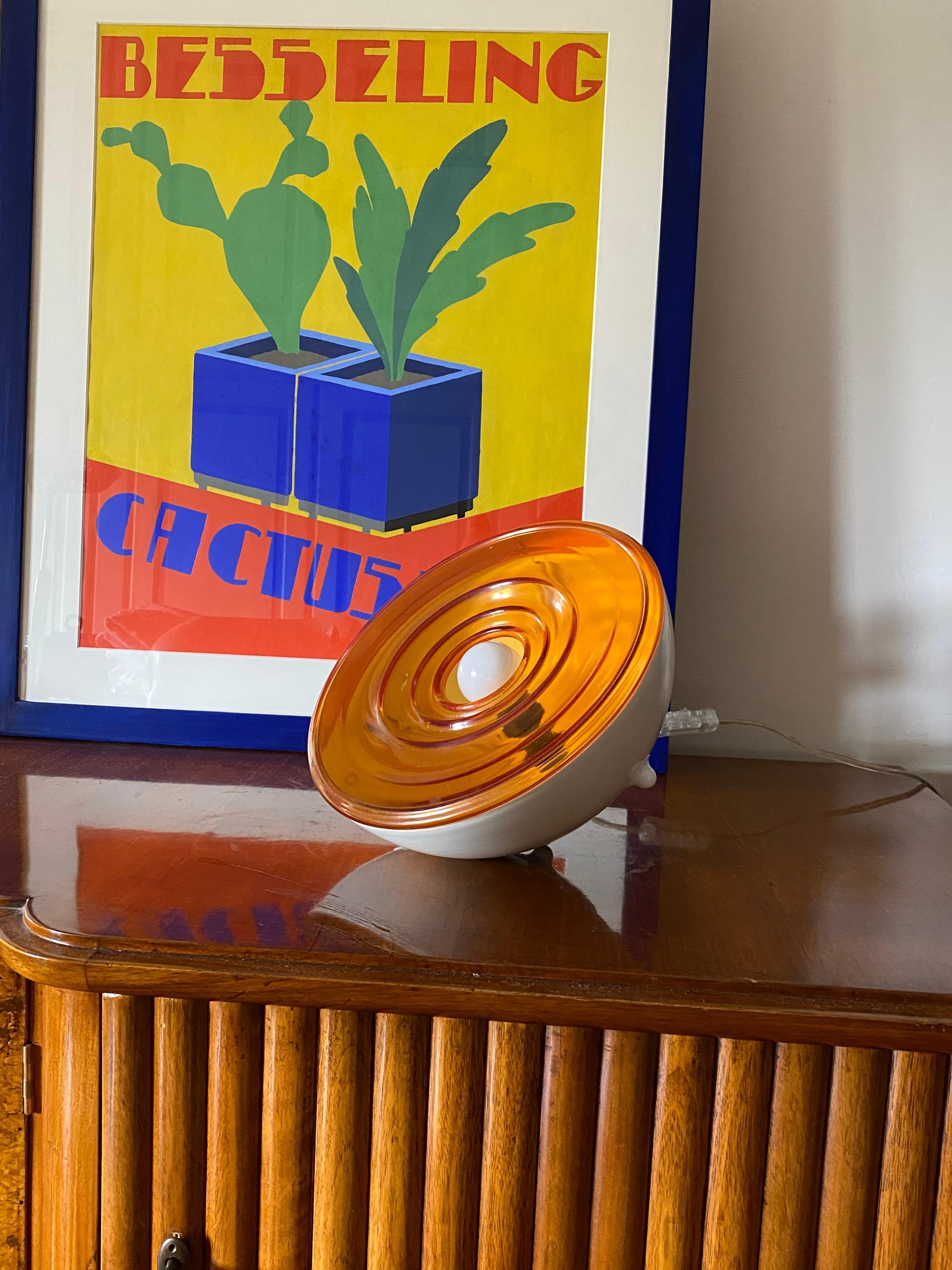 Lampe de table en verre orange de l'ère spatiale

France années 1970

Verre orange. Aluminium laqué. 

23.5 / 13,5 cm H - 26 cm diam.

État : excellent, sans défaut
