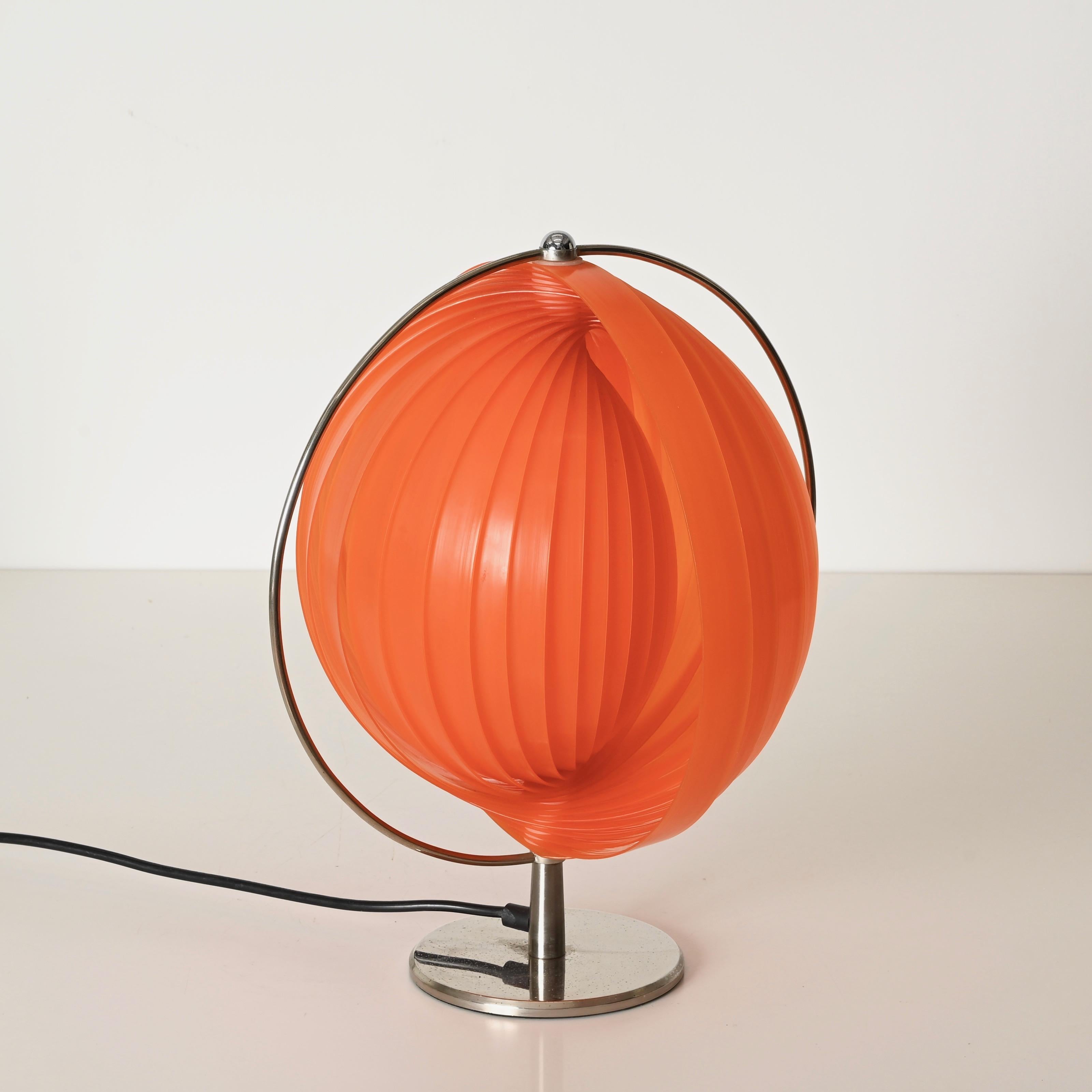 Impresionante y exclusiva lámpara de sobremesa de la era espacial en el icónico estilo de Verner Panton, con una escultural pantalla plisada de color naranja vibrante suspendida dentro de un anillo de metal cromado. Este diseño llamativo y juguetón