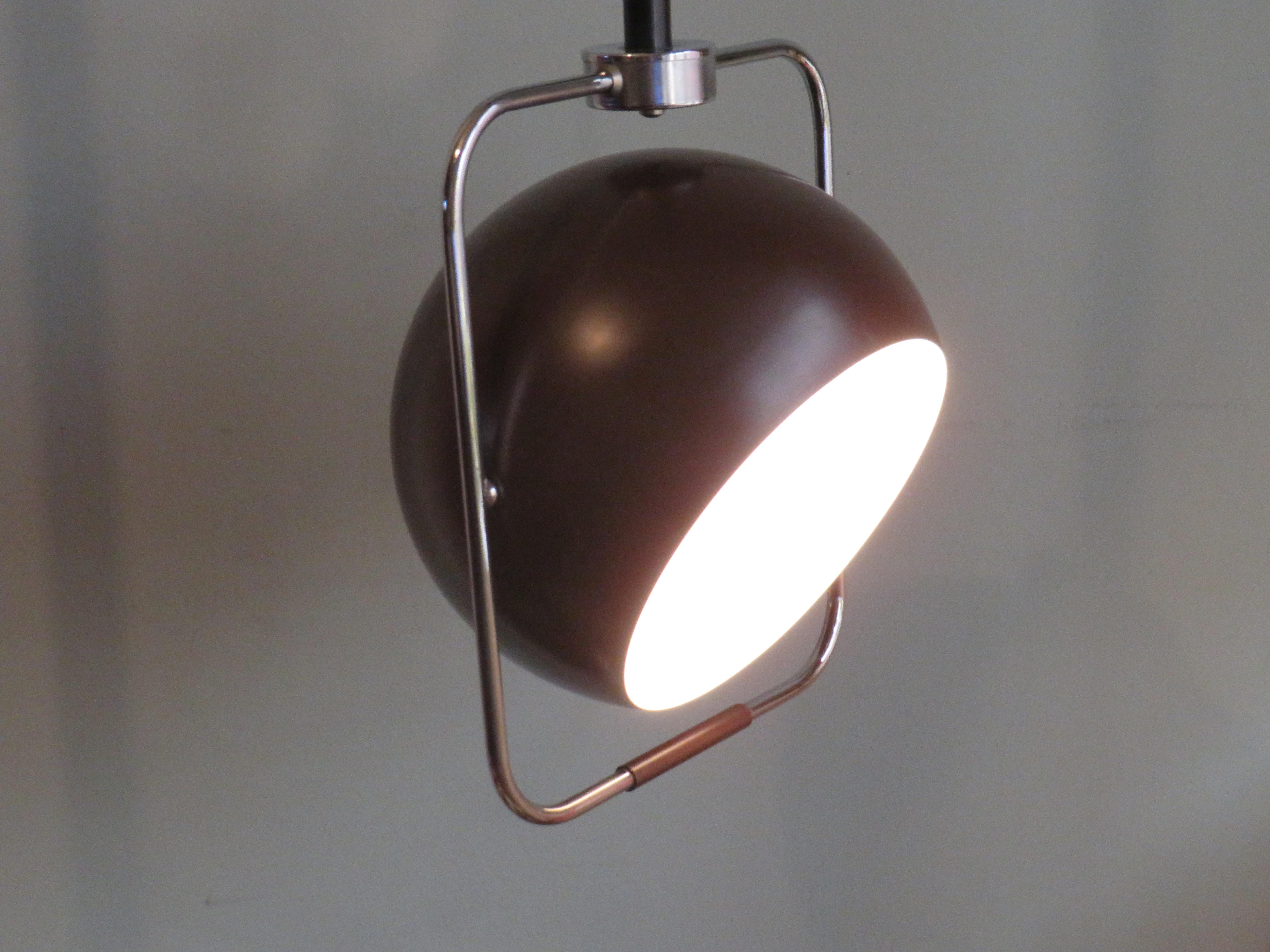 Brown lacquered metal spherical hanging lamp with white lacquered interior in a rectangular chrome frame.
The lamp can be pulled down by the brown plastic handle at the bottom of the chrome frame.
The bulb can also be brought into the desired