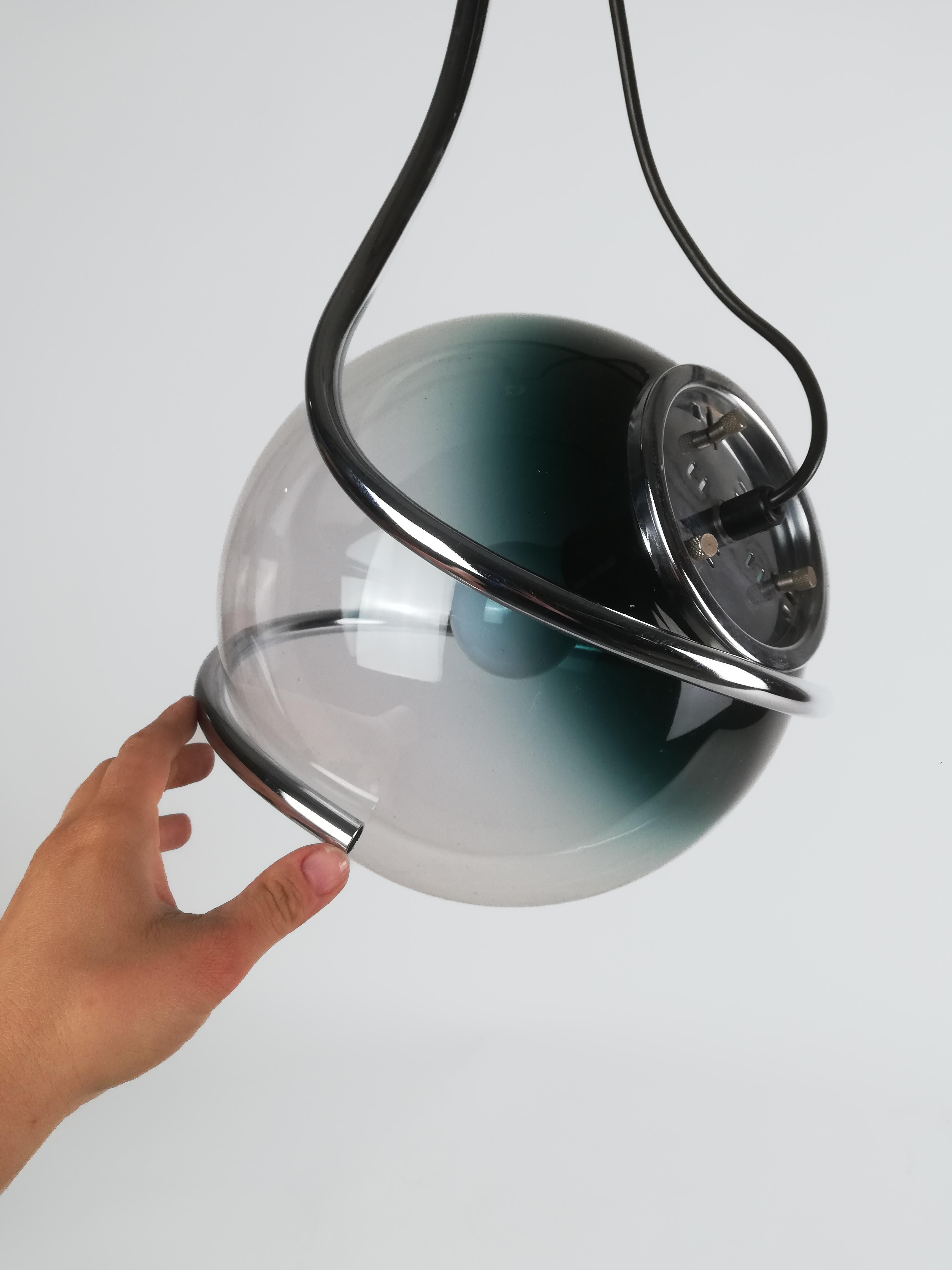 Pendentif Space and Chrome fabriqué en Italie entre les années 1960 et 1970, composé d'une sphère en verre de Murano nuancée de sarcelle à transparente, d'un diamètre de 26 cm, enveloppée et soutenue par un tube en métal chromé qui l'enserre comme