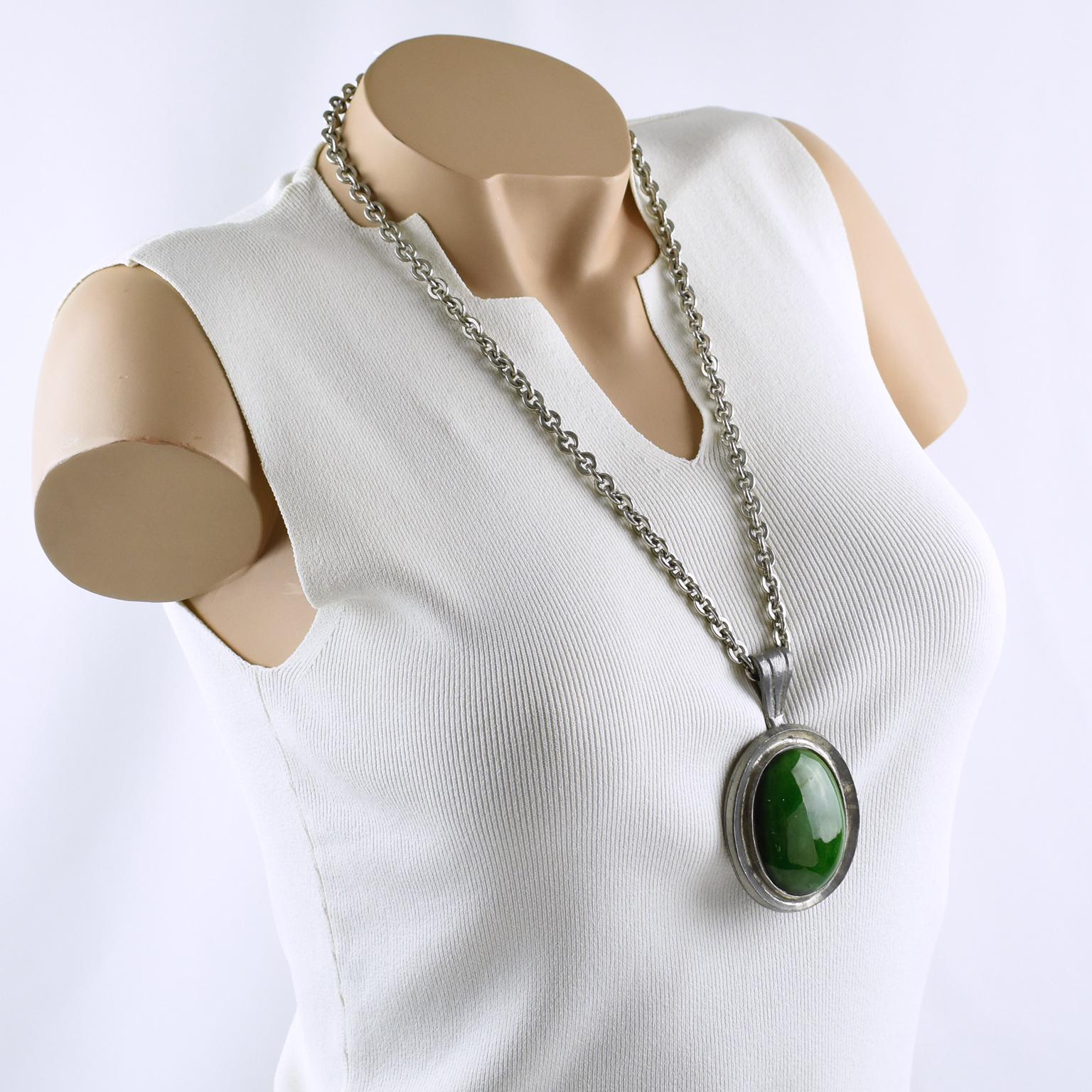 This lovely French Space Age Mid-Century-Modern pendant necklace features a heavy silvered metal extra-long chain complemented by a massive pewter medallion pendant. The pendant is topped with a large ceramic cabochon in a forest green color. There