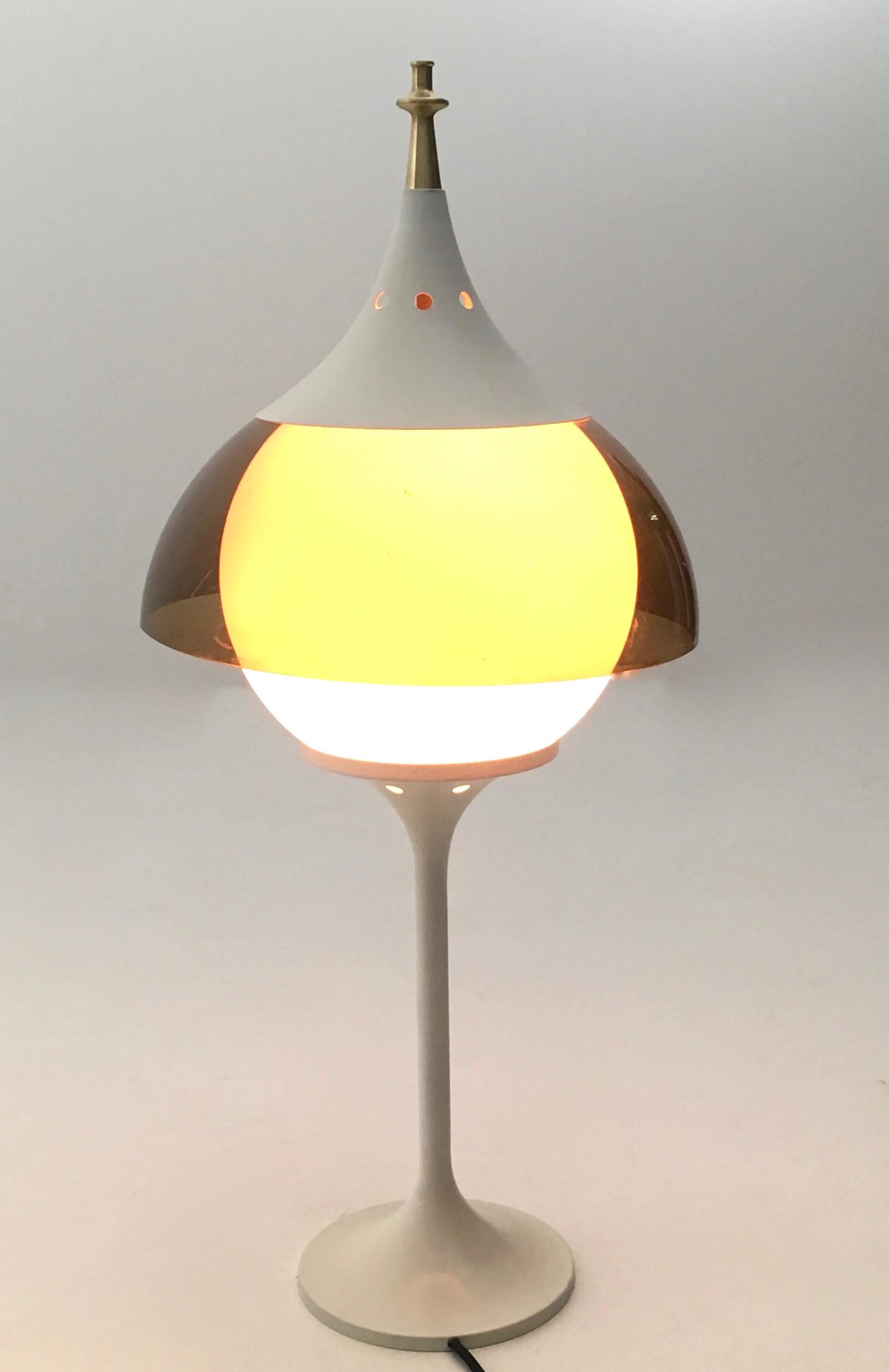 Made in Italy 1970s.
It is made in white varnished metal, opaline glass, plexiglass and turned brass. 
This table lamp might show slight traces of use since it's vintage, but it can be considered as in very good original condition and ready to give
