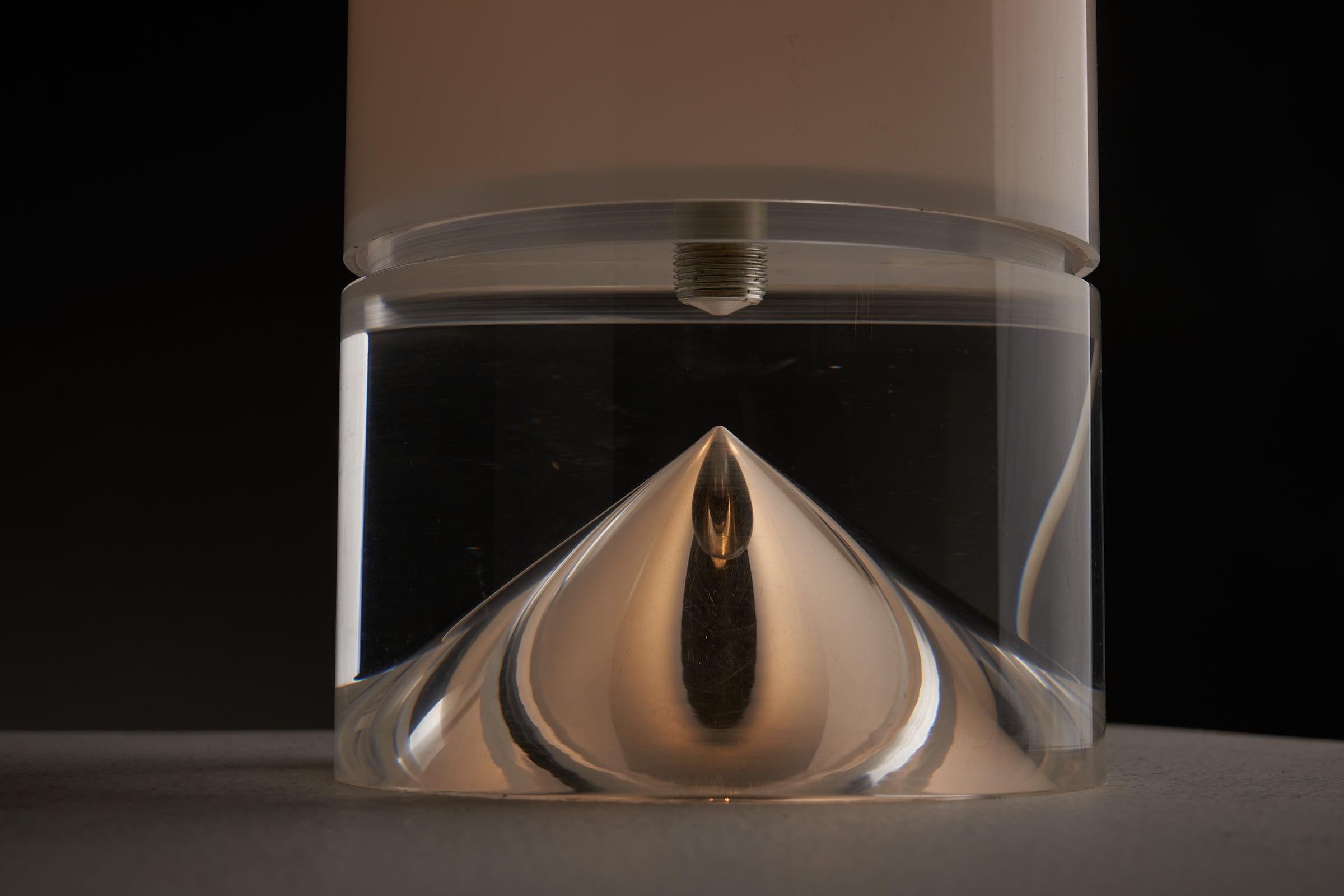 This Space Age table lamp by Cosack is in perfect condition and features a sleek design with two plexiglass components. The upper part serves as the shade, made of opal plexiglass, while the base is a solid clear plexiglass cylinder with a hollow