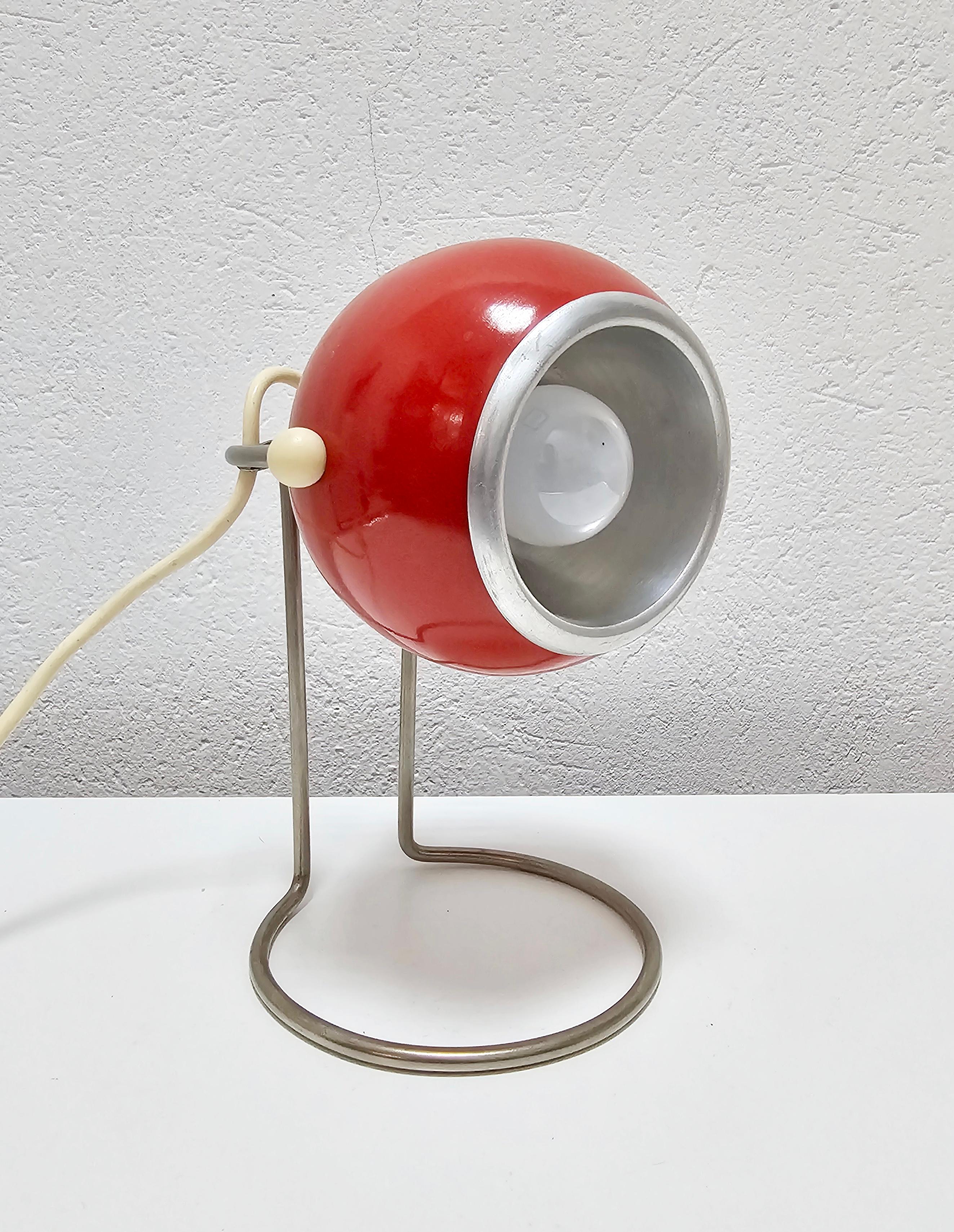 In this listing you will find a striking Space Age table lamp designed by Abo Randers. It features red metal eyeball, which can direct light in different directions, attached to a steel stand. Made in Denmark in 1960s.

Lamp requires a single E14
