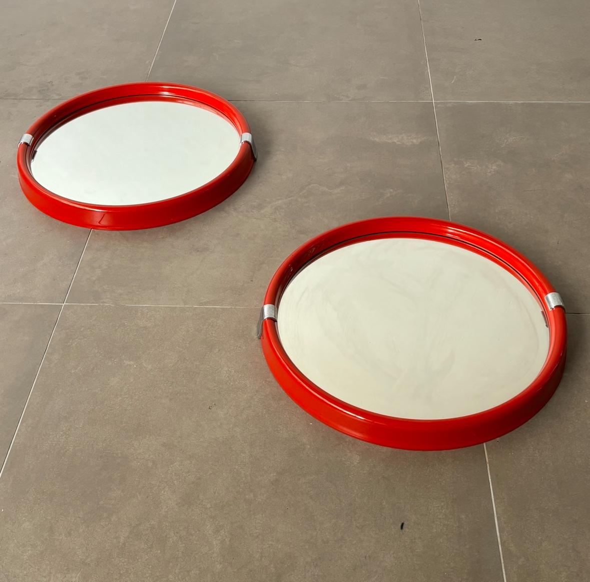 Ce remarquable miroir de l'ère spatiale datant de l'Italie des années 1970 illustre l'esthétique audacieuse et futuriste de l'époque. Le miroir présente un cadre en plastique rouge vibrant complété par des accents chromés élégants, créant un jeu