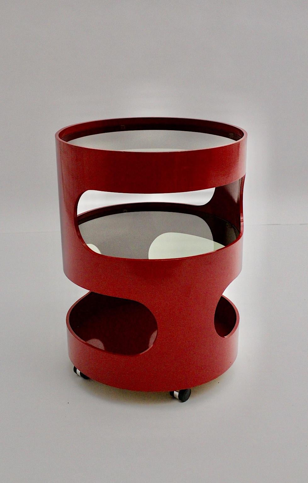 A round shaped two-tiered red vintage side table made of dark red lacquered plywood, which shows 2 round glass plates and 4 wheels.
The vintage condition is very good with signs of age.
Approximate measures:
Diameter 45 cm
Height 62 cm.