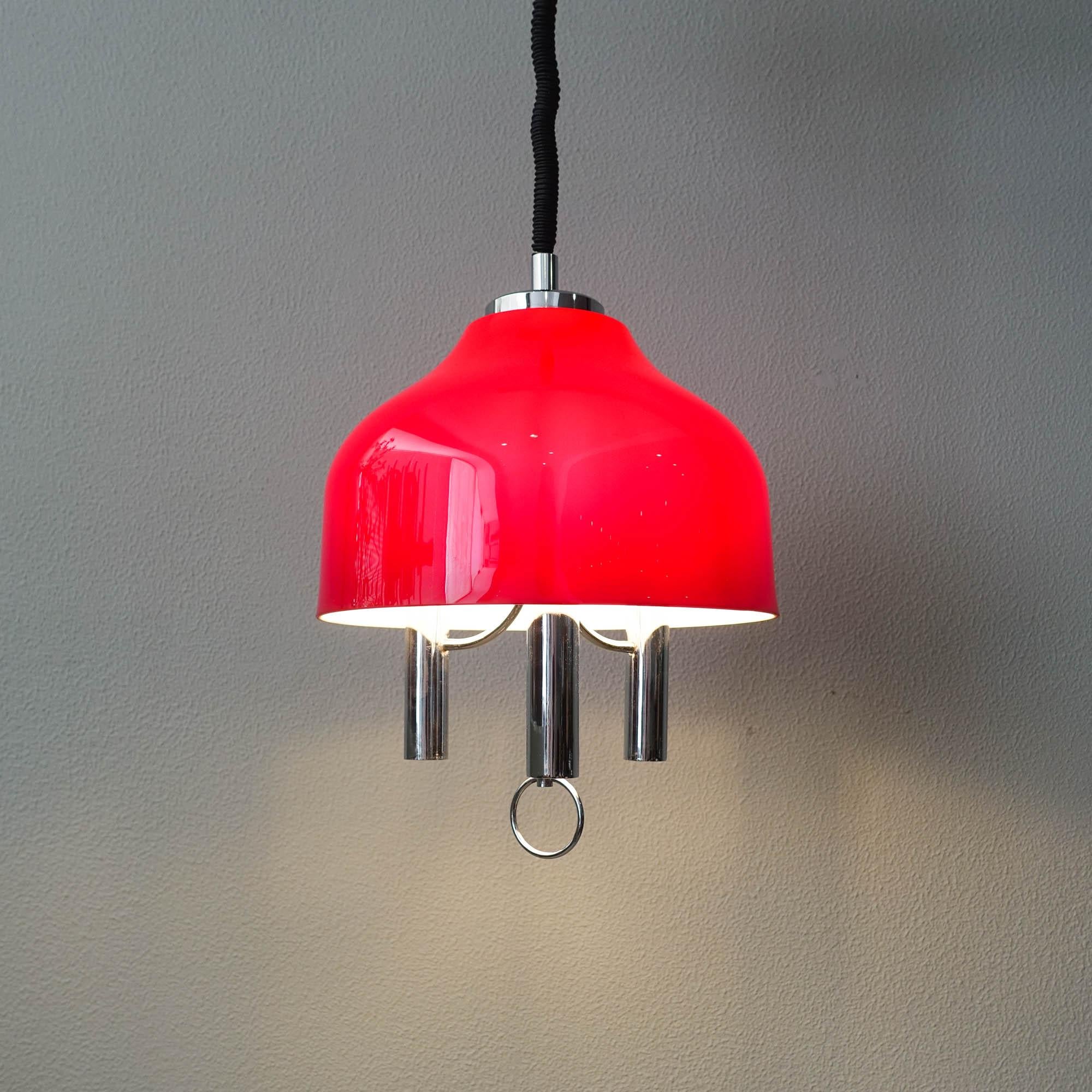 This pendant lamp was designed and produced in Spain during the 1970's. It features a red acrylic lampshade, with white inside, and a chrome structure with three light points. With rise and fall mechanism in good condition and a chrome pull in the