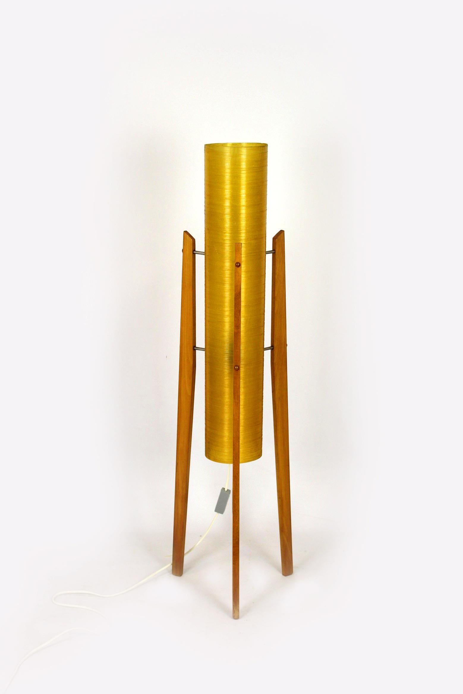 Ce lampadaire fusée a été produit dans les années 1960 en Tchécoslovaquie. 
L'abat-jour est en fibre de verre jaune et repose sur trois pieds en bois. 
La lampe est entièrement fonctionnelle.