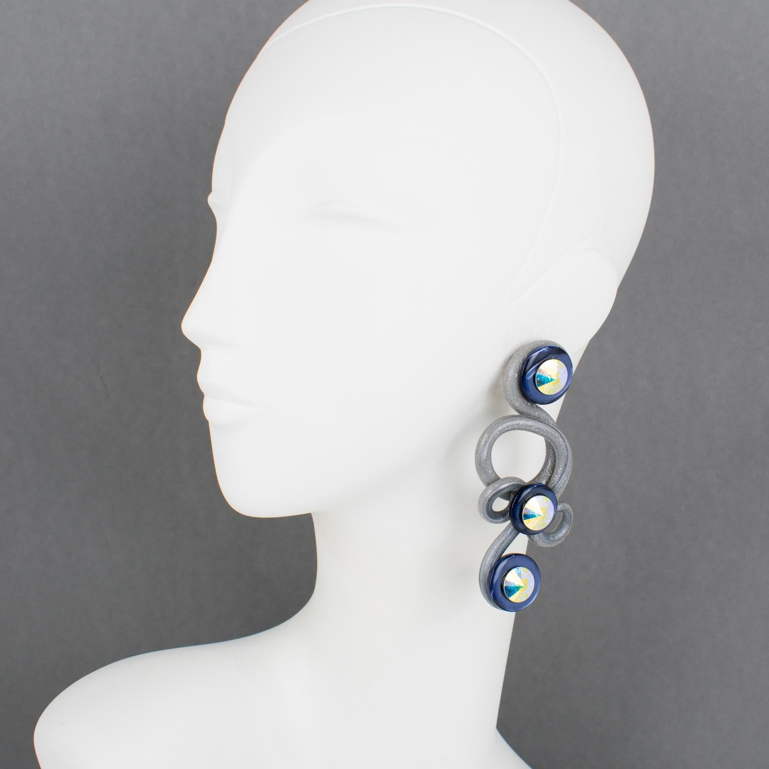 Questi favolosi orecchini a clip sono stati realizzati a mano in Francia negli anni Ottanta. La loro enorme forma a spirale è ornata da dischi di lucite blu perlata, gomma indurita grigia glitterata intagliata e modellata e strass di cristallo AB