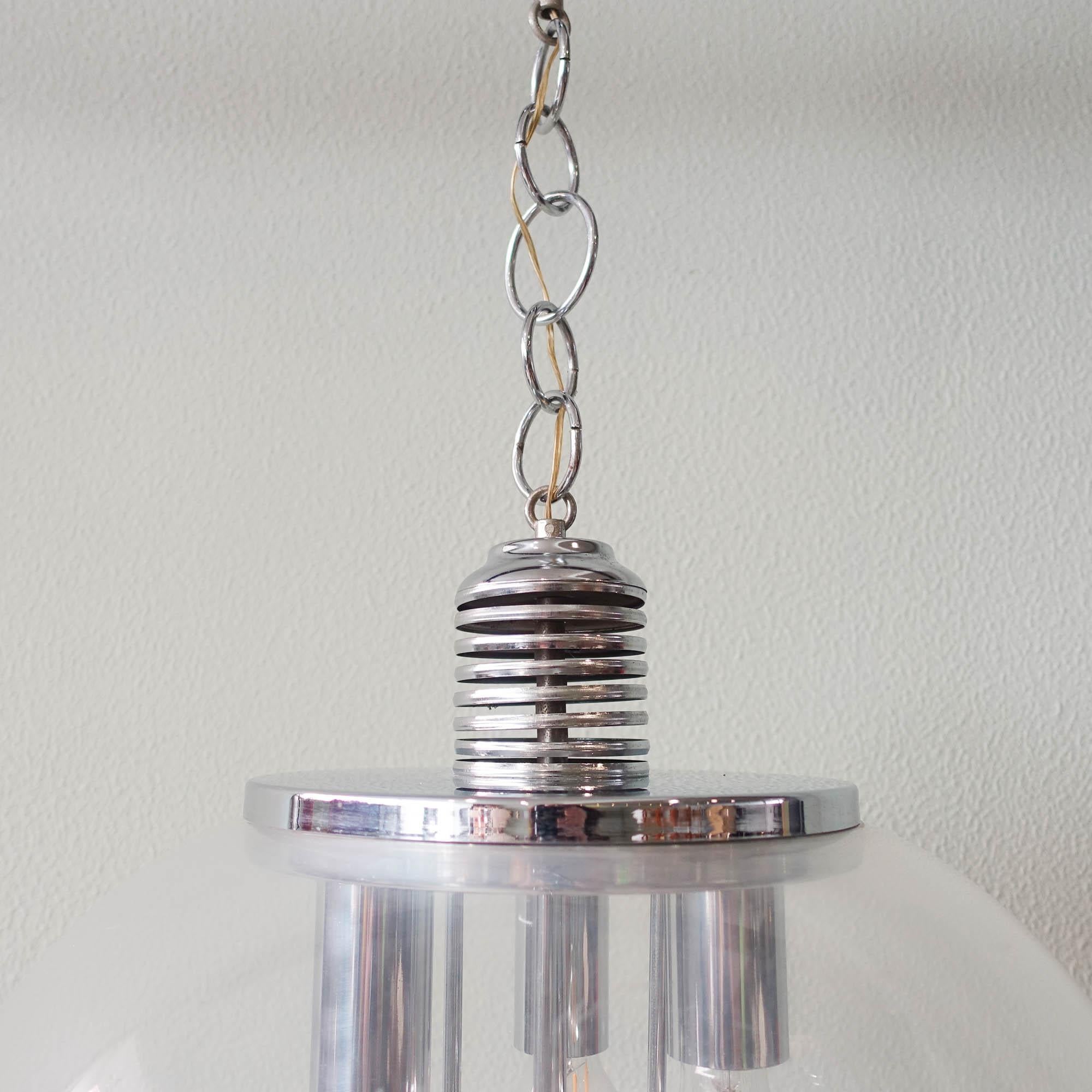 Cette lampe suspendue a été conçue et produite en Allemagne dans les années 1970. Le demi-globe est composé d'un acrylique transparent et à l'intérieur d'une partie métallique chromée avec 3 raccords E27 chromés à l'intérieur ainsi que 4 boules