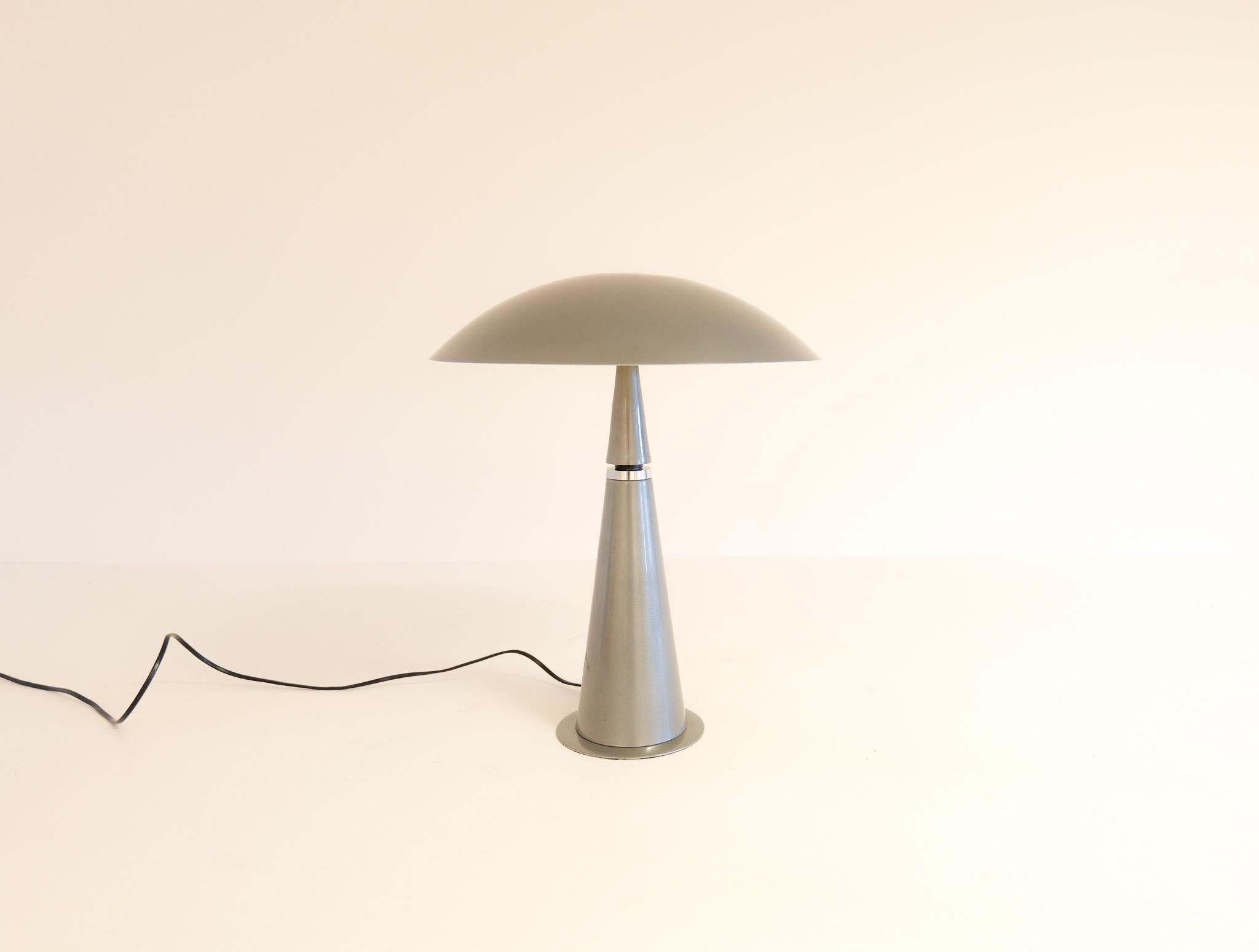 This wonderful table lamp was produced in France for Aluminor during the 1990s. With its cone formed base and mushroom rounded shade it’s a futuristic designed piece that will give that edge to any desk or table. The lightning is turned on by
