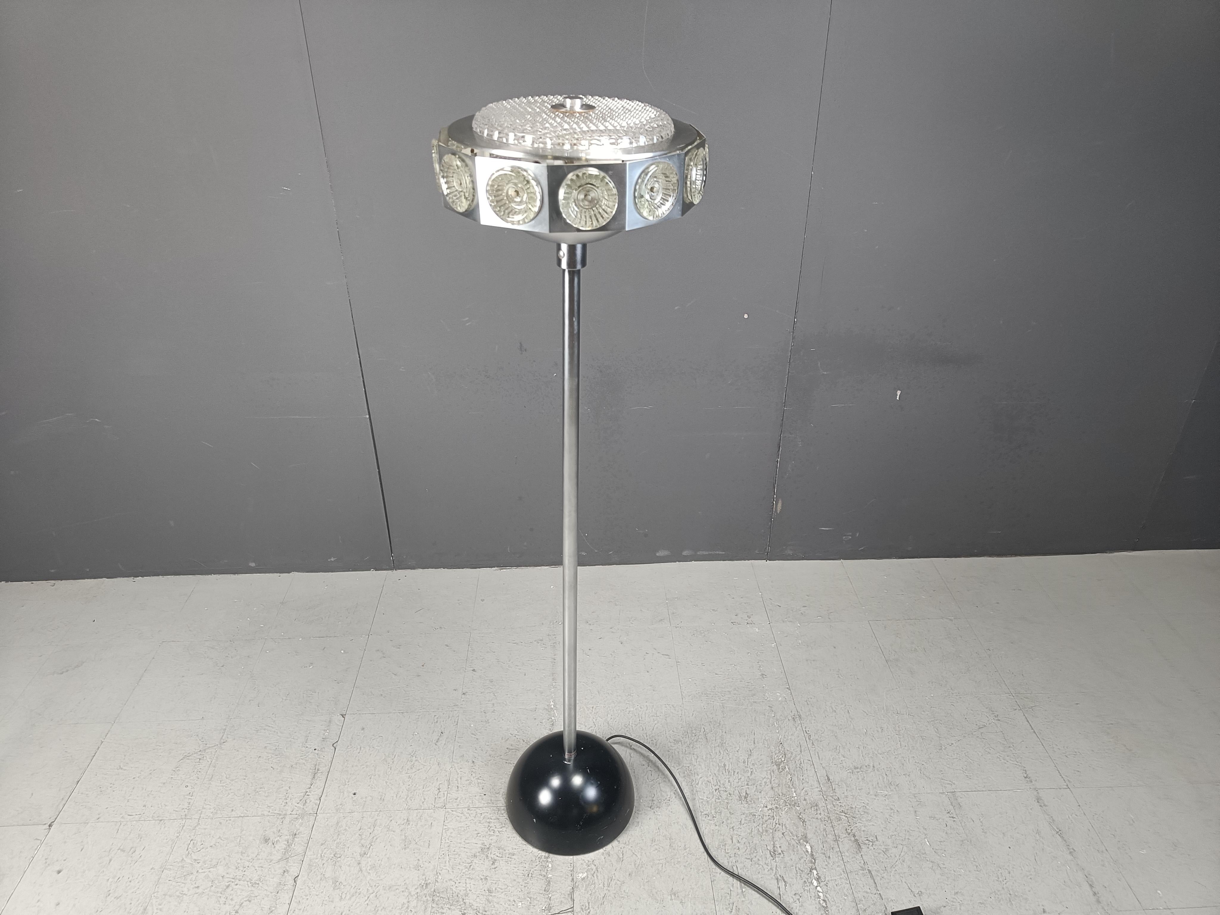 Lampadaire ufo seventies space age design composé d'une tige en métal chromé, d'une base en plastique noir et d'un abat-jour en verre et aluminium.

L'abat-jour émet une lumière très froide grâce au verre prismatique.

Années 1970 - Belgique

Très