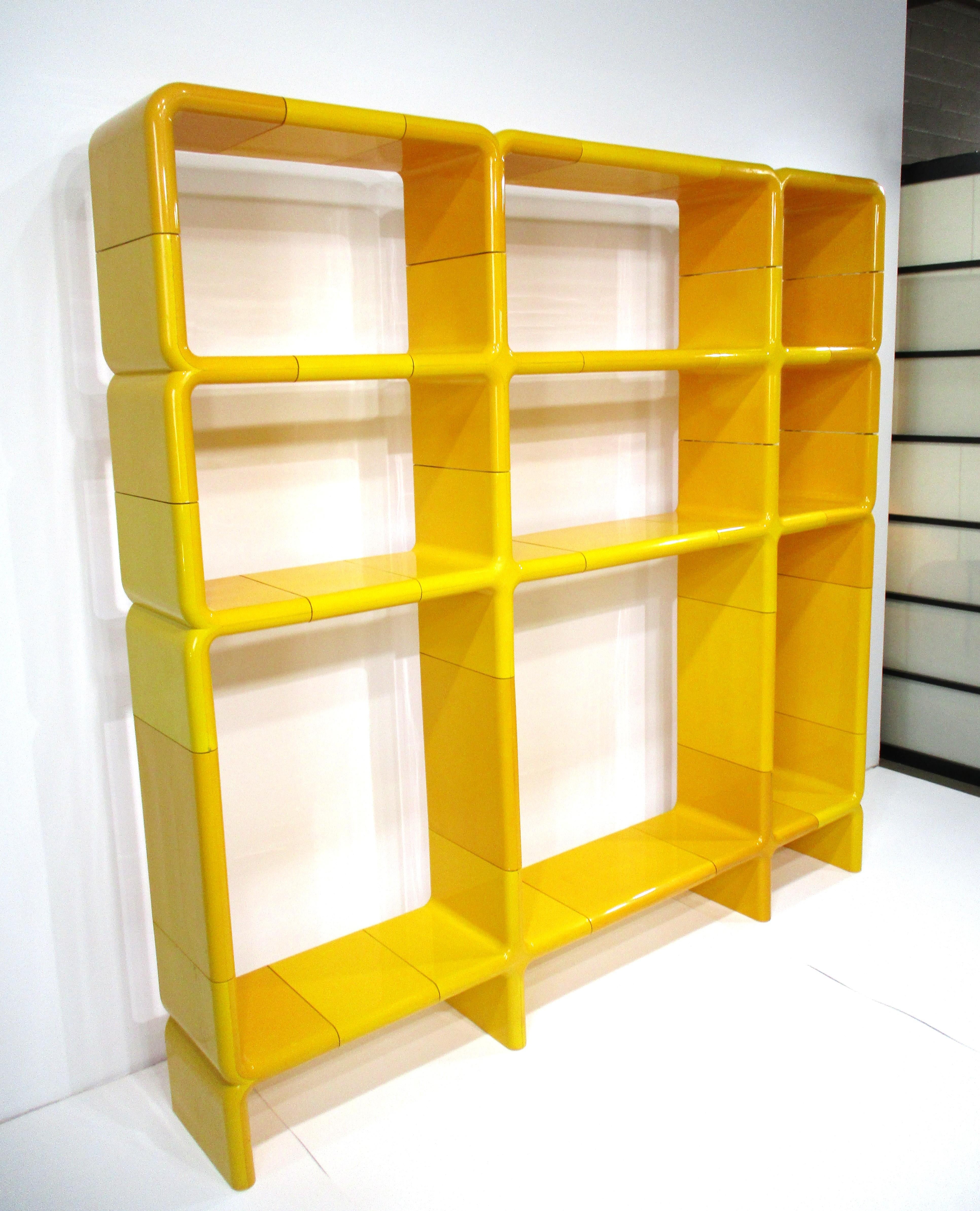 A Umbo Space Age modular shelving unit in a molded yellow ABS styled plastic containing 28 pieces making for a large unit . Fitting together like a puzzle with inner pegs you can create different forms and shapes , this is the form that the former
