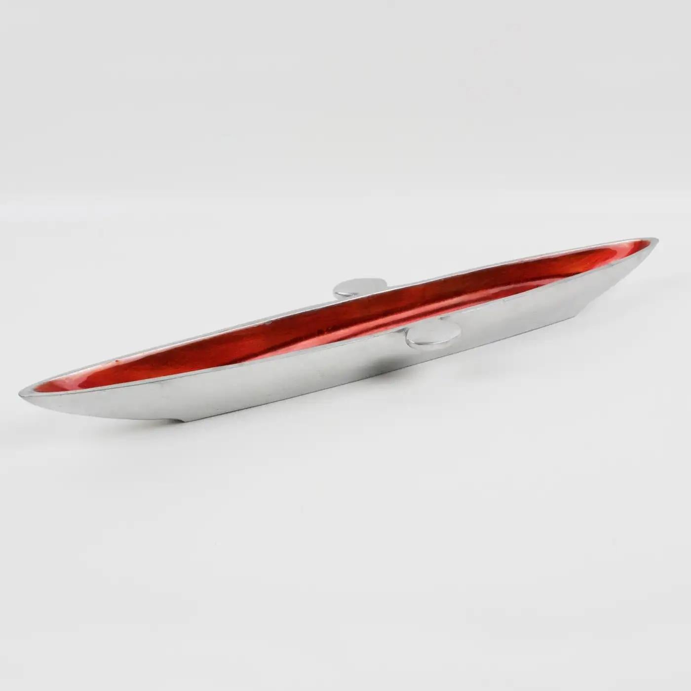 This striking modernist Space Age aluminum bowl, vide poche, was crafted in the mid-20th century in France. The elongated canoe-shaped piece has a typical spatial ship design. The catchall is polished cast aluminum and lined with a bright red-orange