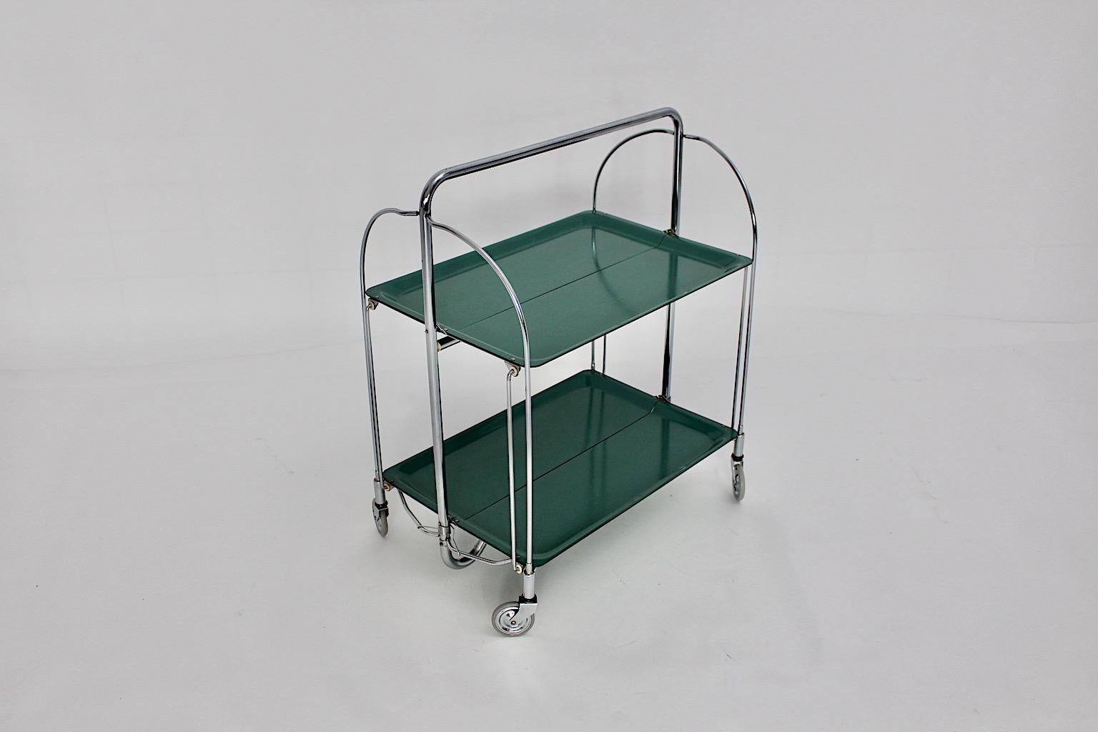 Space Age vintage bar cart or serving trolley from green formica plates and chromed metal frame 1970s.
Throughout its foldable parts on each side great to use in various dimensions. Four rubber wheels feature mobility.
Very good condition with