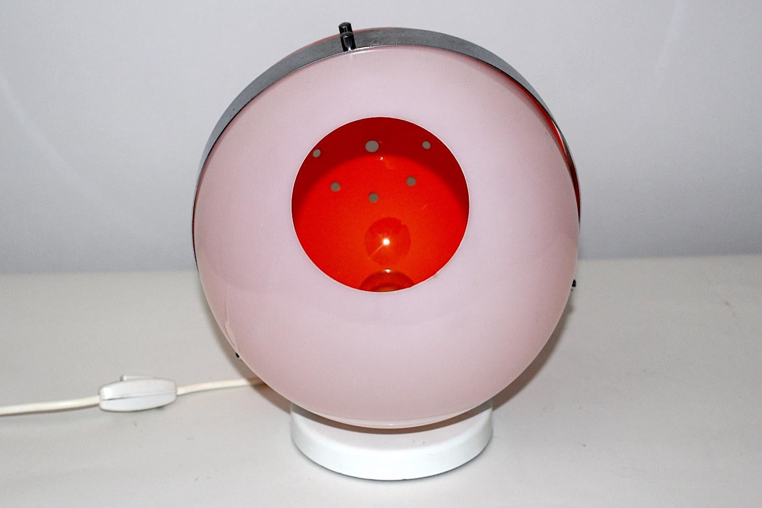 This Space Age vintage orange and white table lamp shows a chromed metal band. 
Also the vintage orange table lamp features one E 27 socket.
The vintage condition is very good.
Approx. measures:
Diameter 26 cm
Height 31 cm.
 