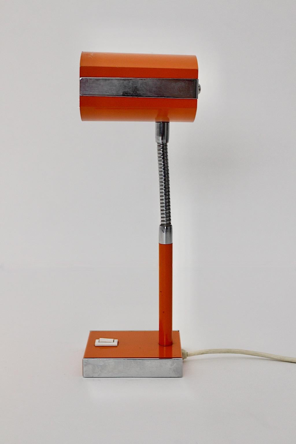 Space Age vintage desk lamp from metal in orange and silver color tones 1960s Germany.
A wonderful table lamp or desk lamp in playful orange color with a flexible silver stem and a rectangular base from the 1960s.
The table lamp shows an on/off