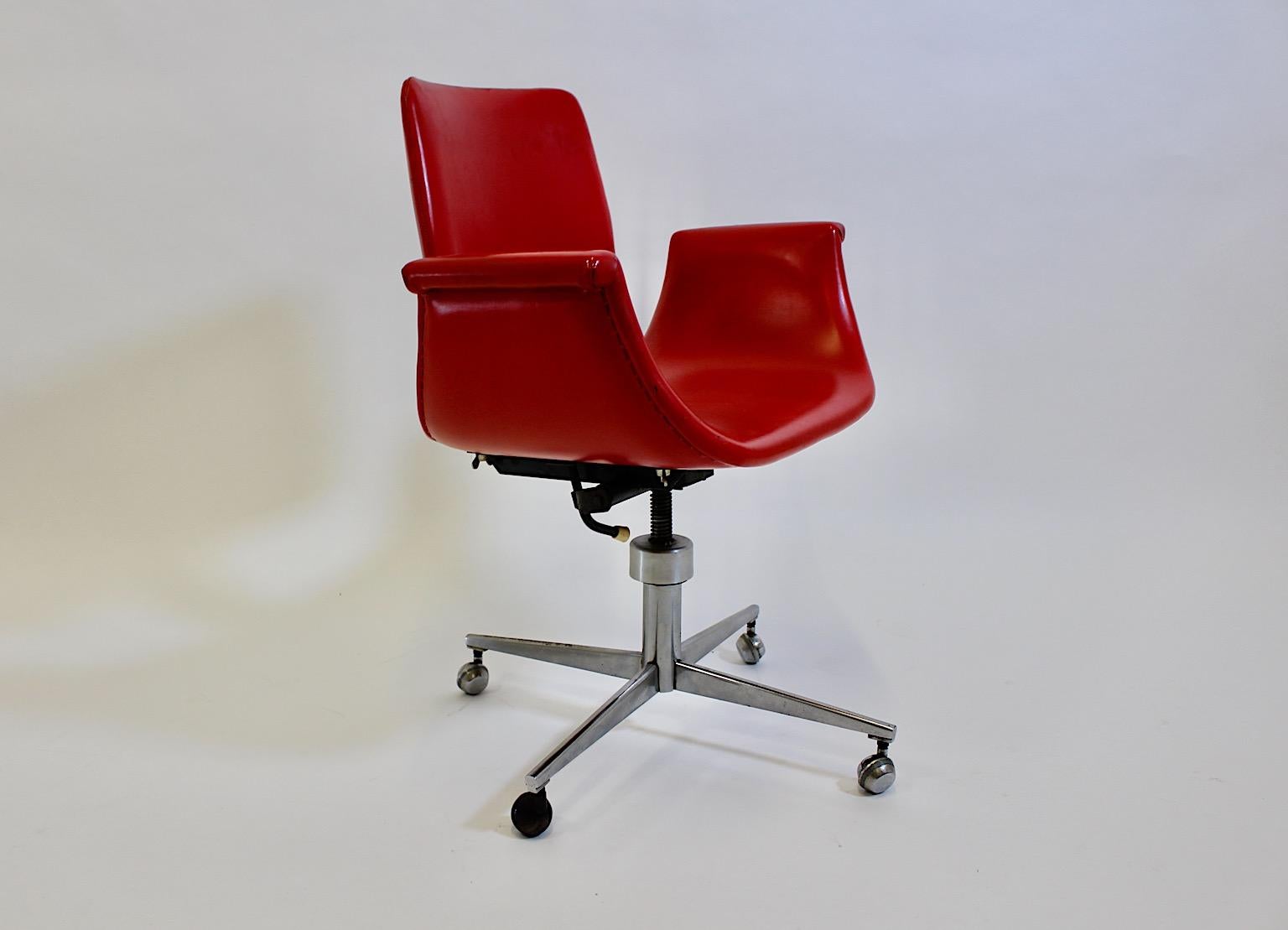 Space Age vintage office chair or desk chair from red faux leather and chrome in tulip shape 1960s.
A fabulous vintage office chair or desk chair with a red curved seat shell in iconic tulip shape covered with red faux leather, while the bottom