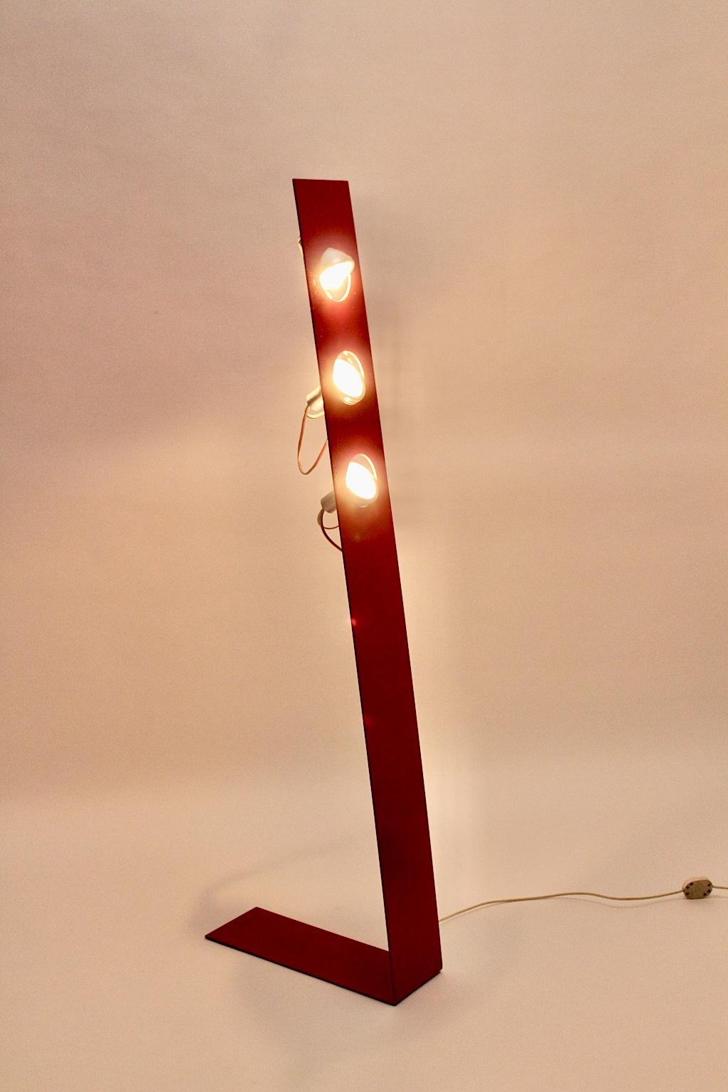 Space age vintage red metal floor lamp designed and manufactured 1960s, Italy.
The amazing floor lamp features a red kinked metal base with three E 14 sockets.
The lights are adjustable.
Also the floor lamp shows an on/off foot switch. 
The