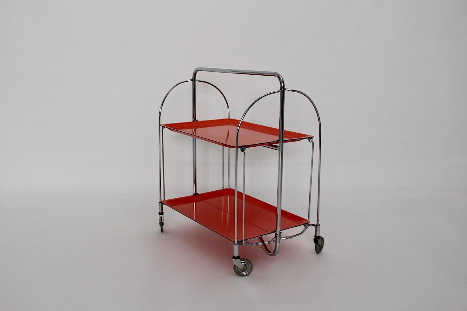 Chariot de service vintage de l'ère spatiale ou chariot de bar ou guéridon dans un ton de couleur joyeux rouge orange à partir de stratifié et de métal.
Le chariot de bar est pliable. Pour une bonne mobilité, le chariot de bar est doté de 4