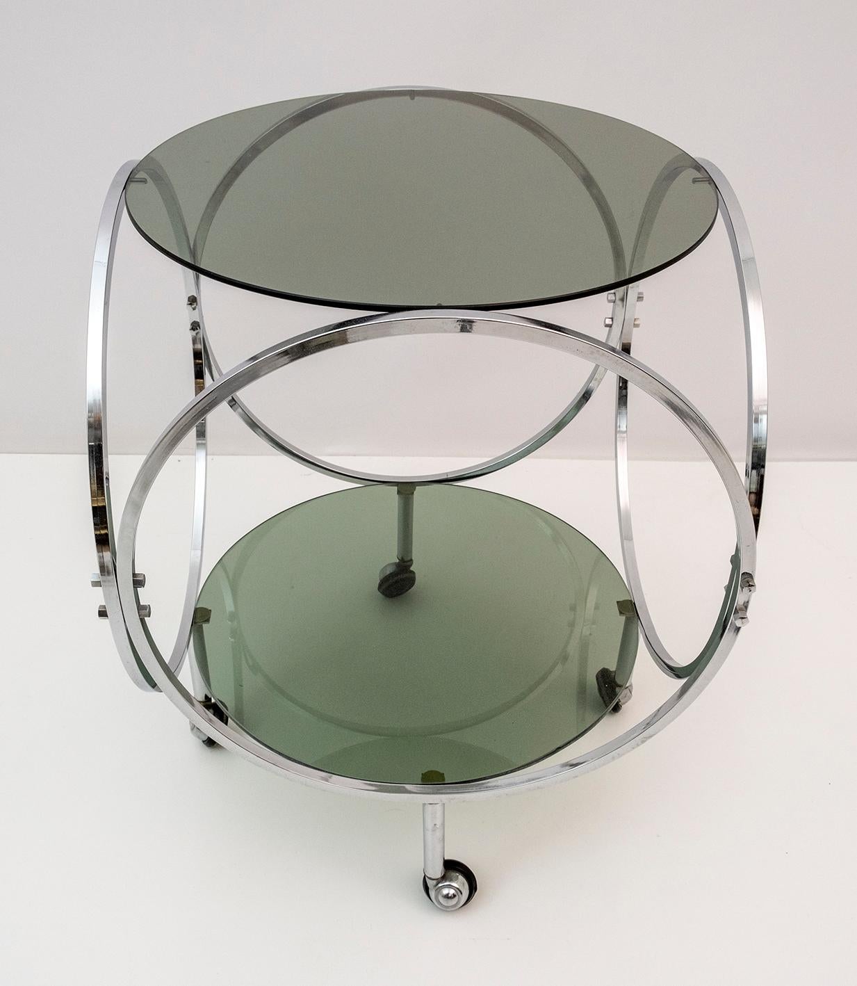 Space Age vintage coffee table in chromed metal and smoked glass from the 70s.
While the chromed metal base displays a beautiful curved construction, the smoked glass tops feature a round shape.