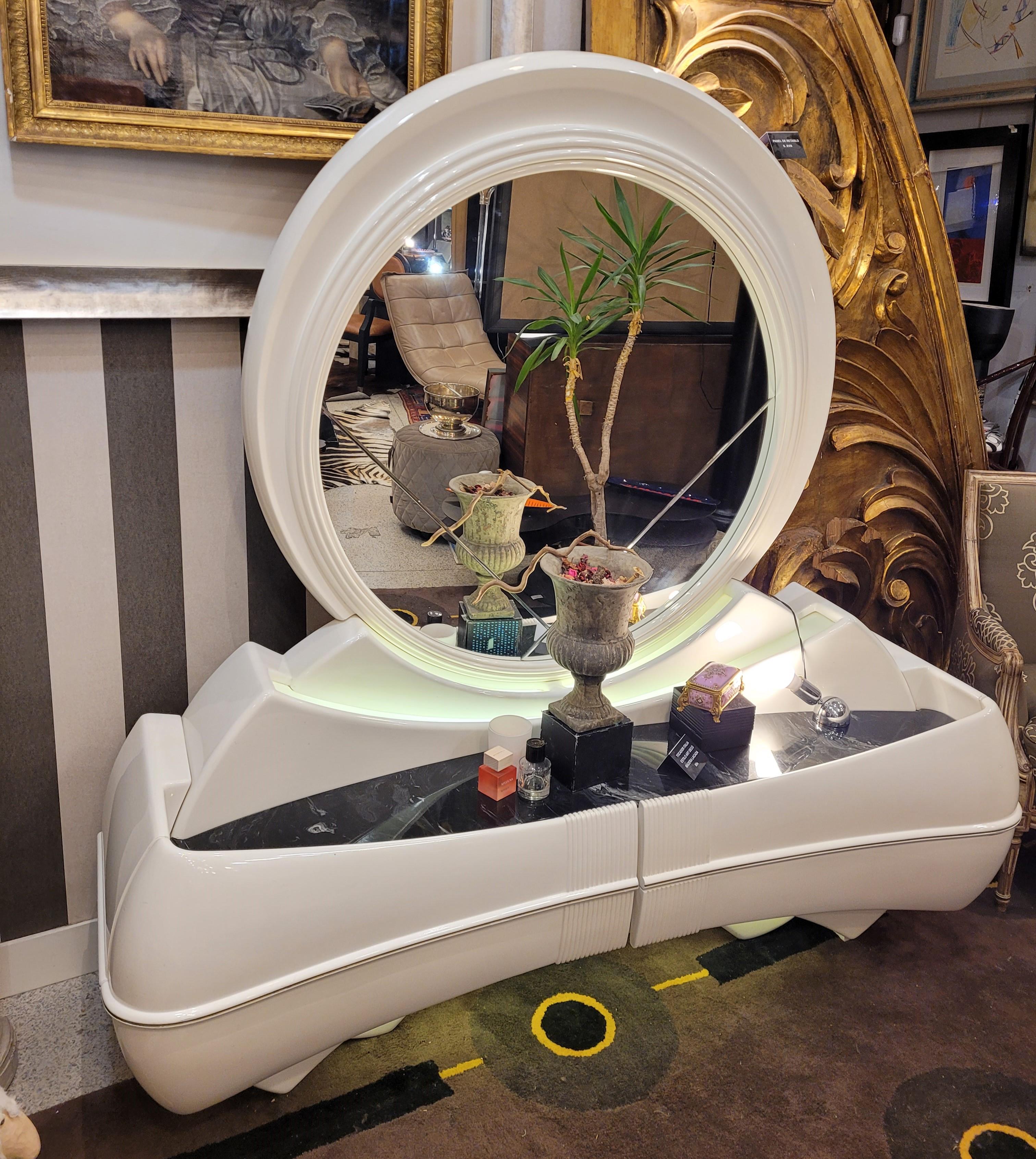 One of a kind dressing table, space age style, 70s, with great influence of Art Deco aesthetics.
In white lacquered wood, with a black marble effect fiberglass top. Large circular mirror in the upper part and the storage part is divided into two