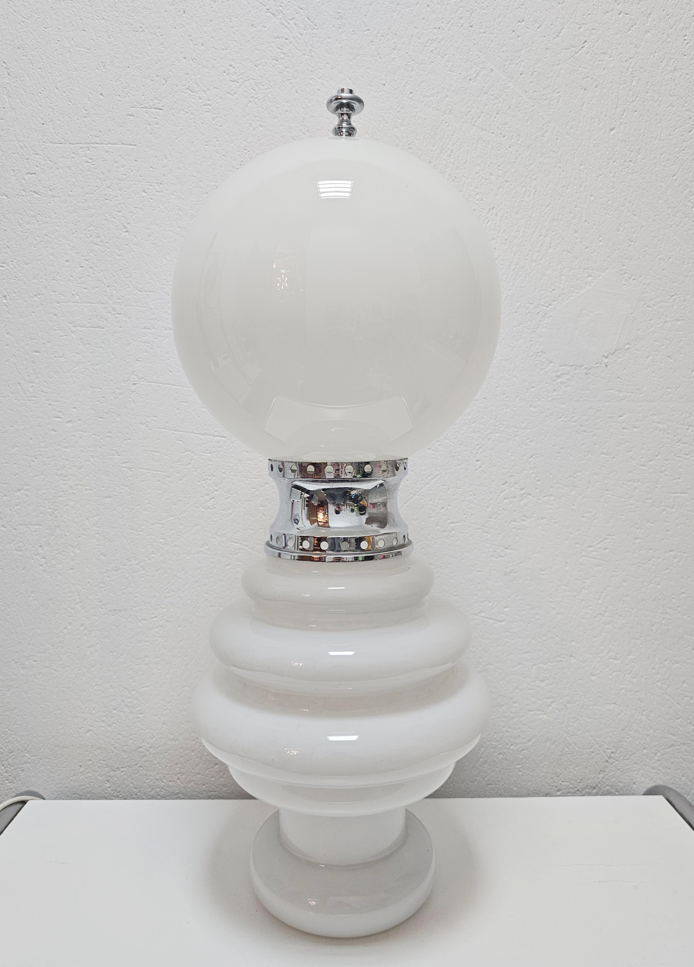 In this listing you will find a rare Space Age floor or a large table lamp designed by Carlo Nason for Mazzega. It is made of two white Murano glass parts that are connected with a silver ring. Each part of the lamp is lit by a pair of E14 light