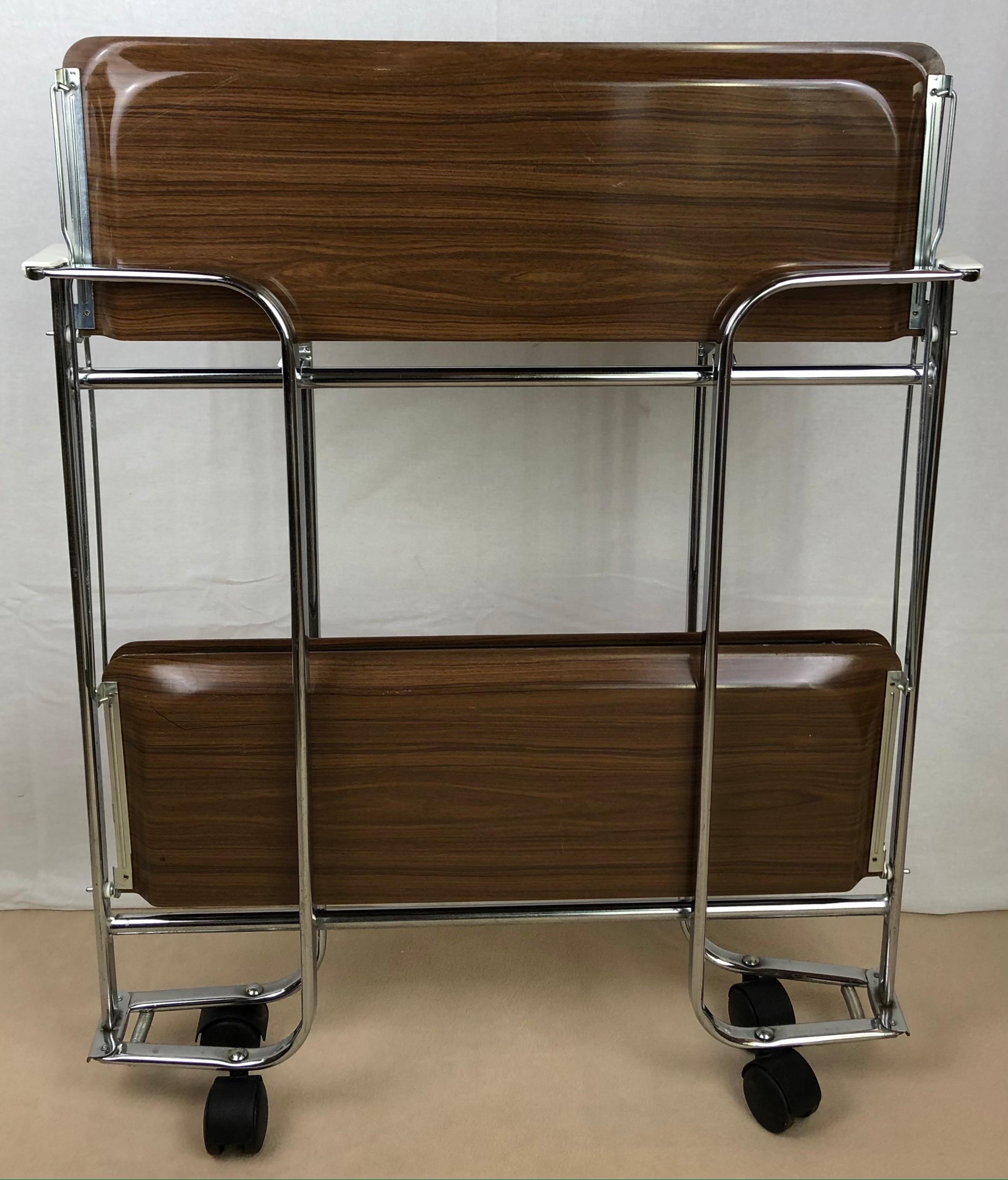 Hard to find, rare and original French bar cart from La Maison Dinett, Paris, circa 1970s. Folding, chrome-plated metal and plastic faux wood. Versatile stylish piece of vintage design. 

It can be folded and therefore easily stored (great space
