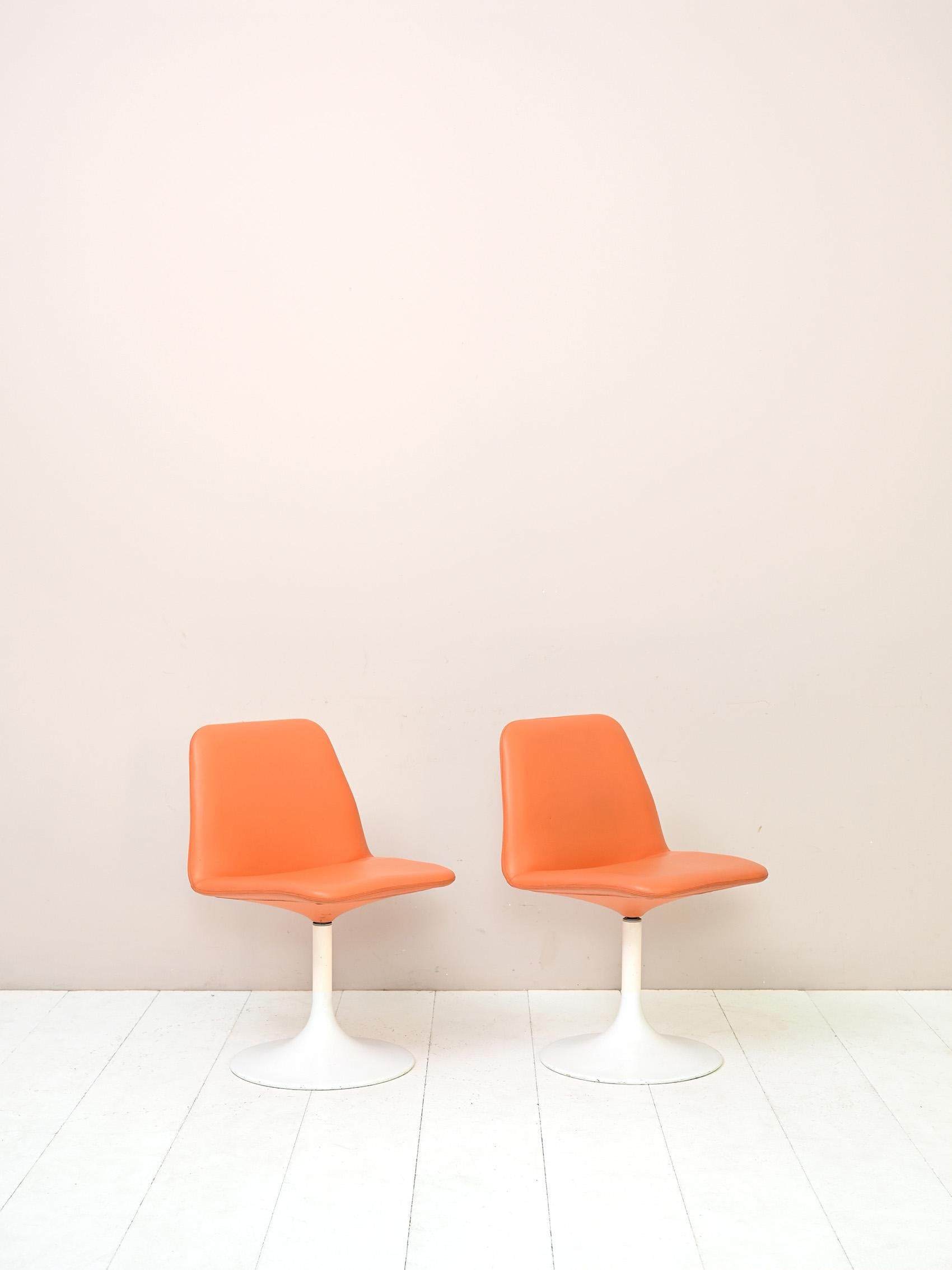 Pair of original vintage Scandinavian chairs.

These modern and original spaceage style chairs feature a white metal base on which the upholstered swivel seat, lined with orange faux leather, interlocks.
Perfect for the office or as head