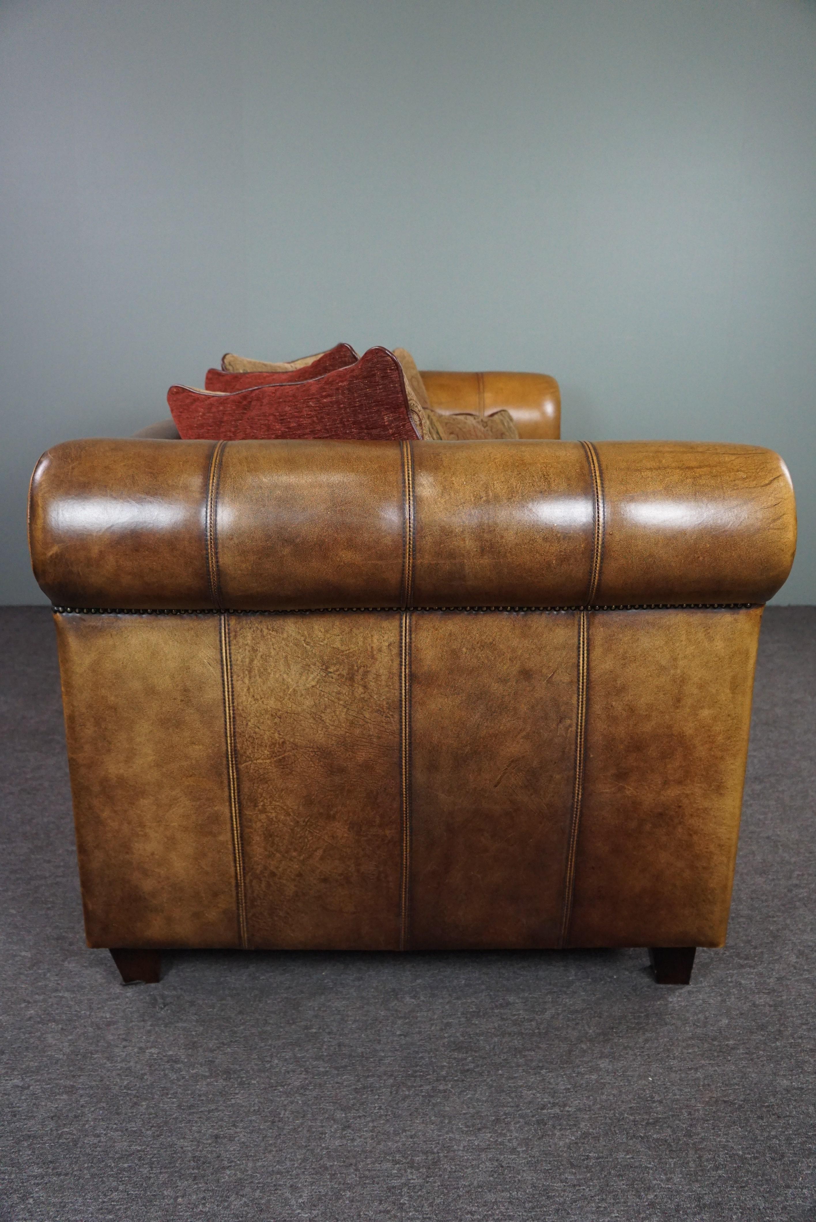 Offered is this beautiful sheep leather sofa with both the appearance and the seating comfort.

The warm-colored fabric cushions make the beautiful deep-colored sheep leather stand out even better and this sofa has the best of both worlds. This