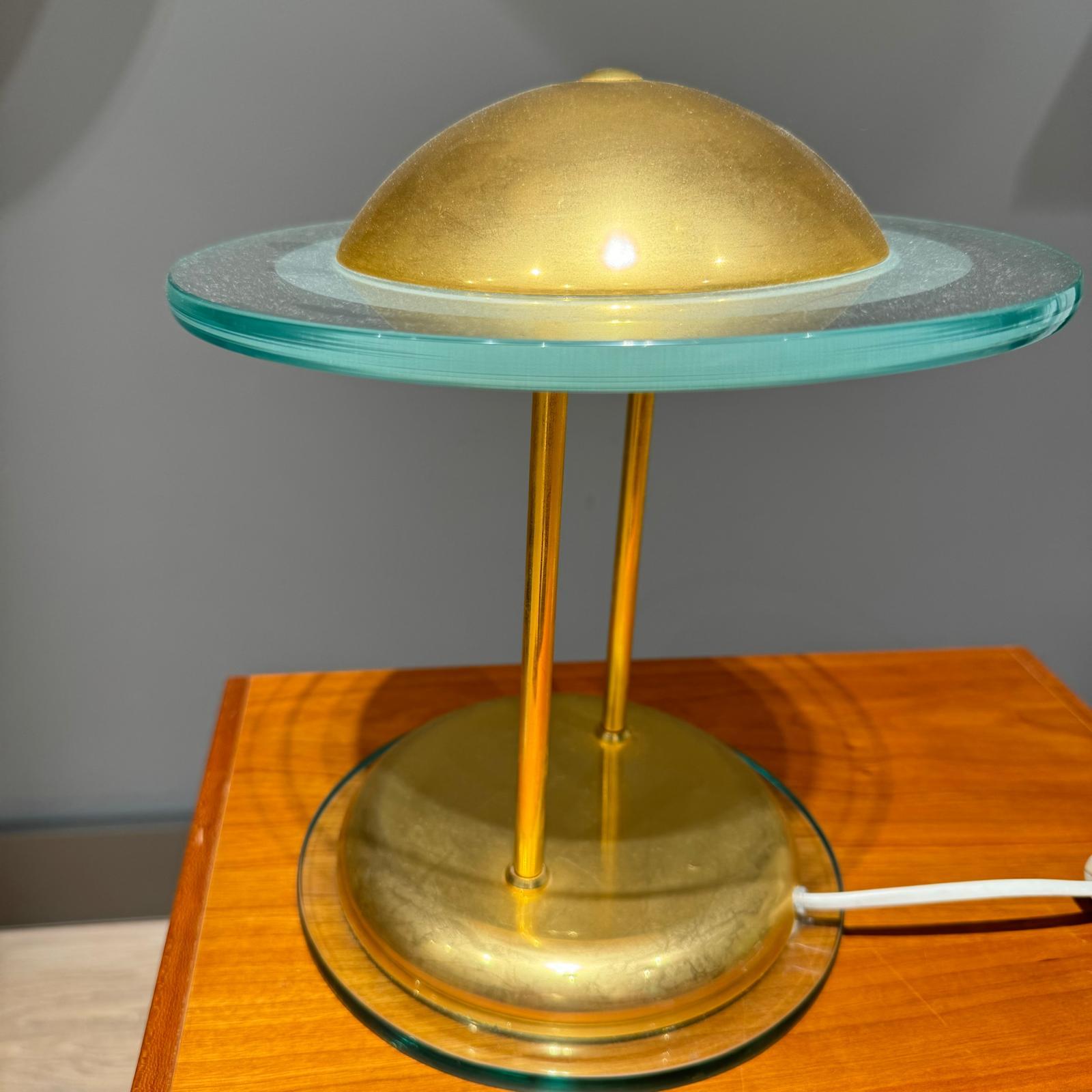 Schreibtischlampe aus Messing und Glas.

Der Hersteller ist Herda aus den Niederlanden. Sehr außergewöhnliches Design aus der Zeit des Space Age!

Sie besteht aus zwei  runde Glasplatten und einen kugelförmigen Aufsatz.

Der Sockel und der Deckel