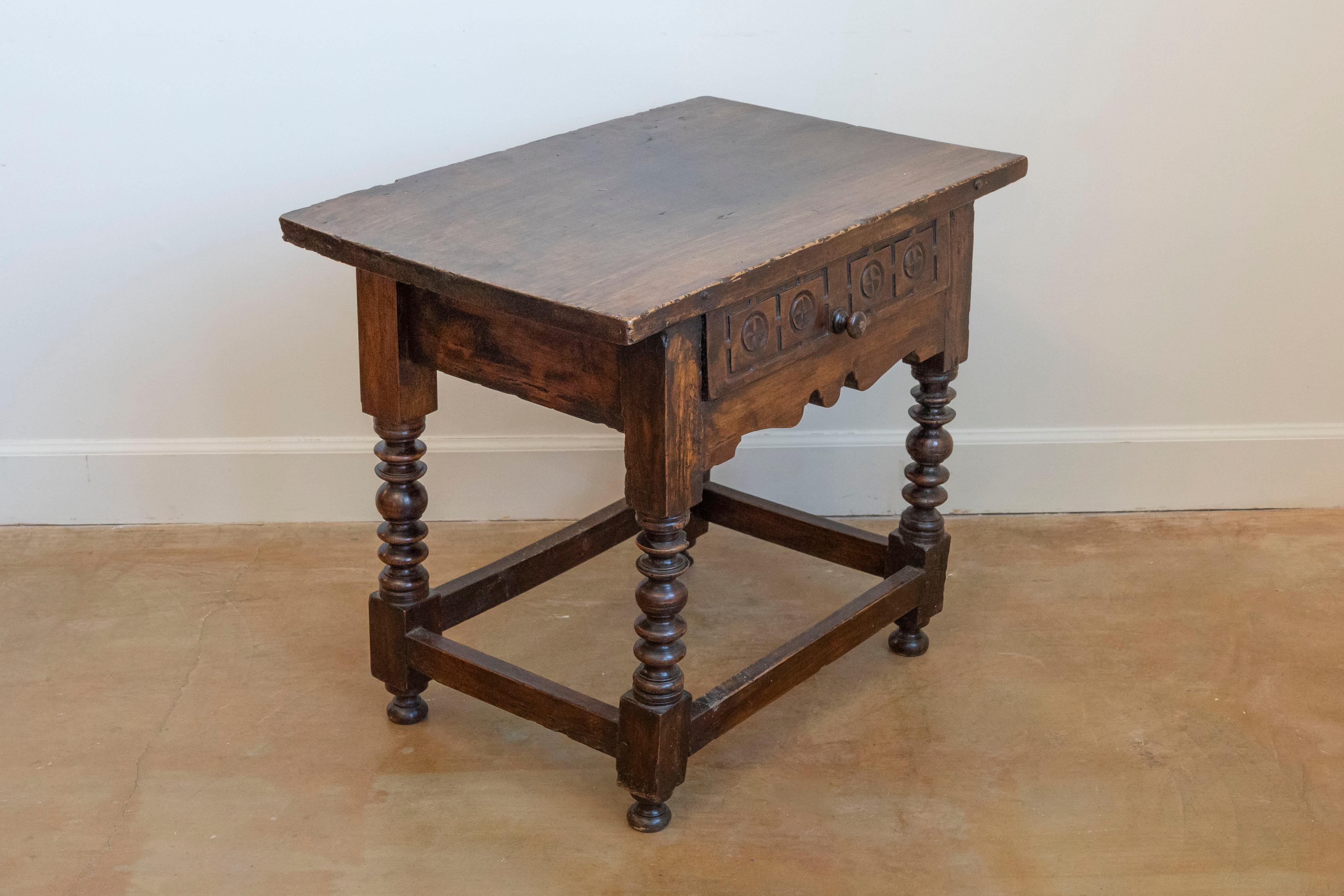 A Spanish spool leg side table from circa 1770 with single dovetail drawer and carved rosettes. This Spanish spool leg side table, hailing from circa 1770, is a remarkable piece of antique furniture that combines utility with historical charm.