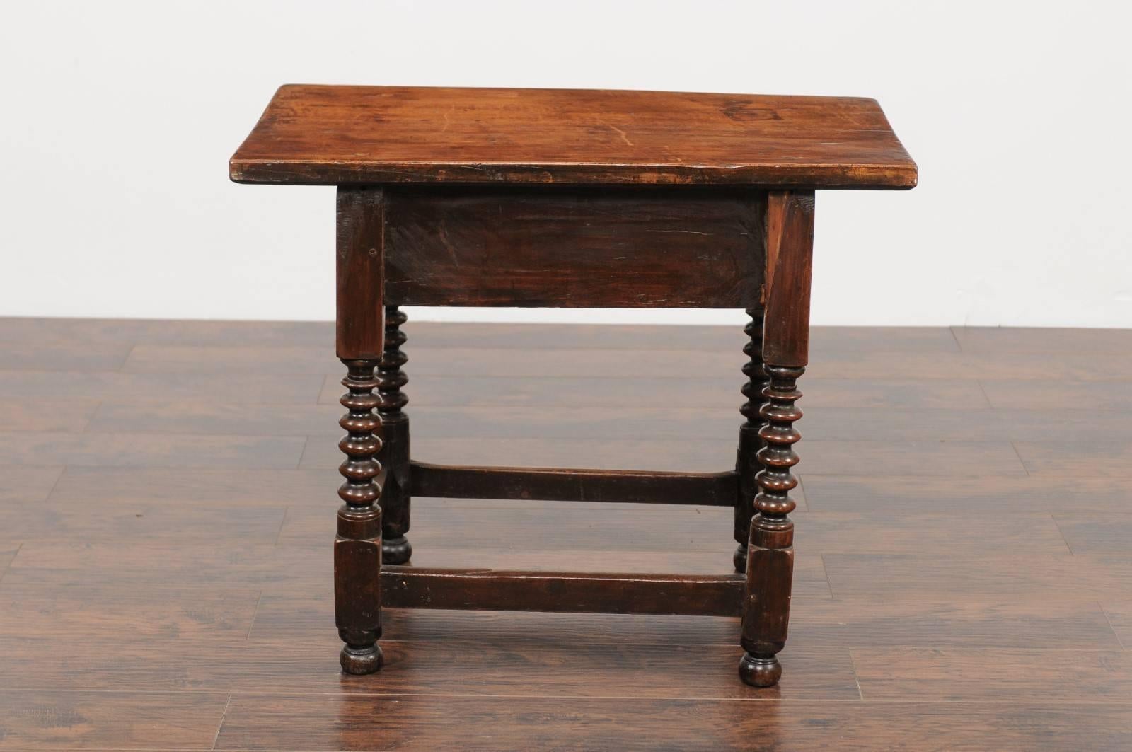 A Spanish walnut side table with single drawer, scalloped apron, turned legs and side stretcher from the late 18th century. This elegant Spanish table features a simple, rectangular top, sitting above a hand-cut dovetailed drawer, adorned with