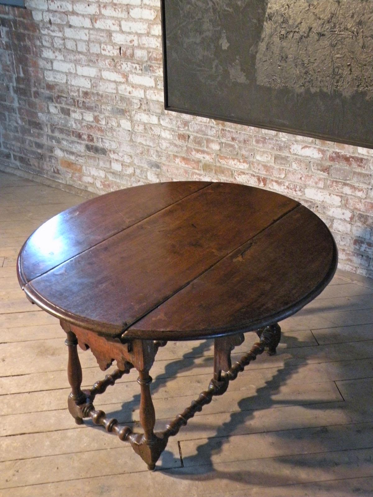 Table espagnole du XVIIe siècle en noyer avec de charmants détails en bois de fruitier incrusté, des pieds et des traverses tournés et des pieds pivotants en forme pour soutenir les feuilles de la table lorsqu'elle est ouverte. La table peut être