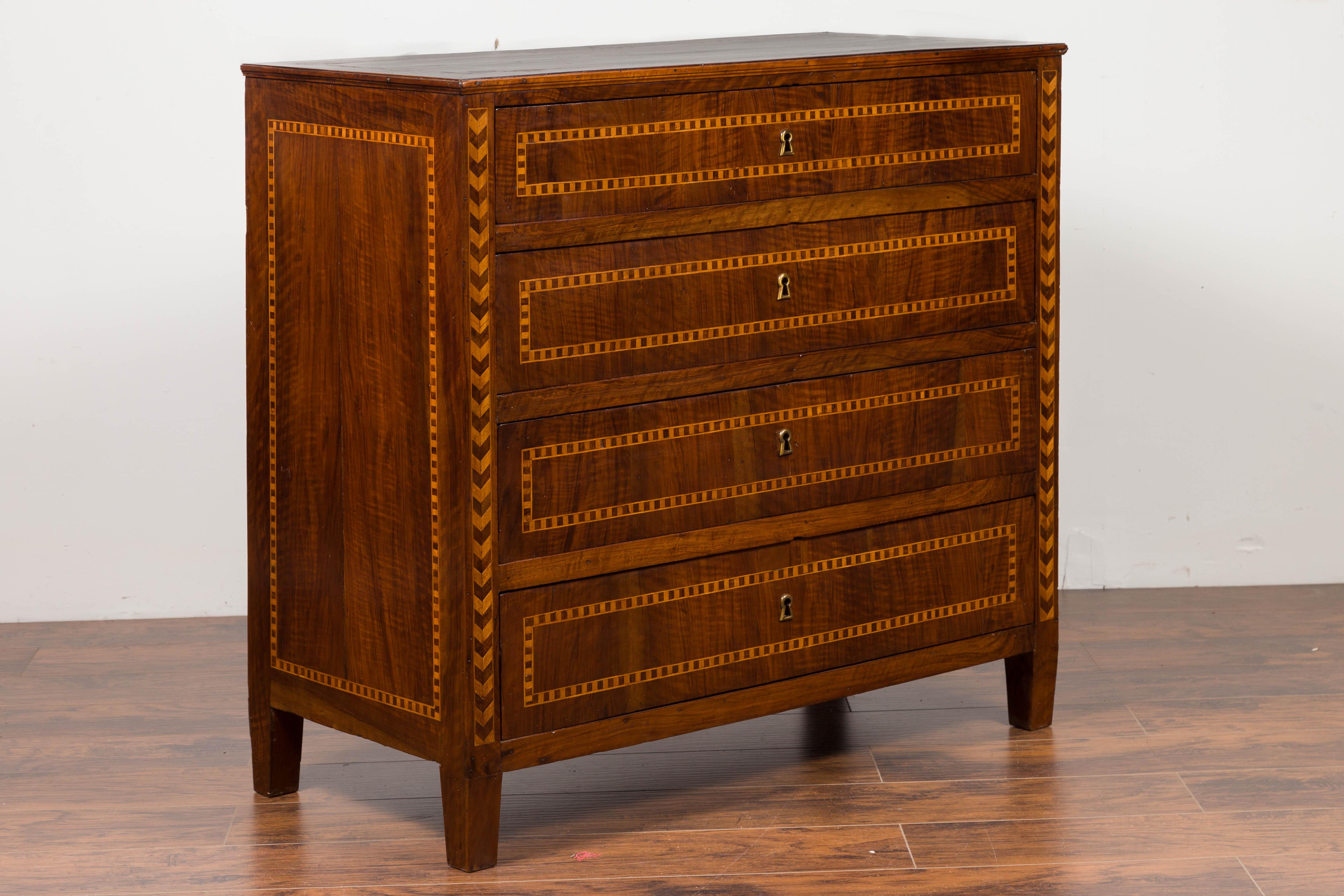 A Spanish walnut four-drawer commode from the mid-19th century, with inlaid accents and tapered feet. Born in Catalonia during the first half of the 19th century, this four-drawer commode features a rectangular top adorned with a geometric inlaid