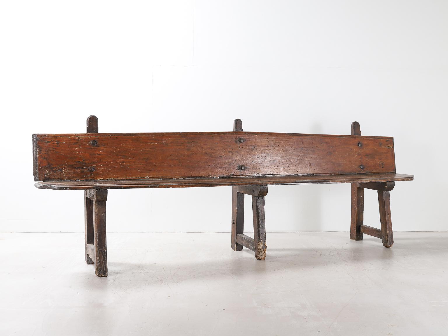 A long Spanish bench with iron rivets, supported by three legs. The legs have some ageing and wear due to age (see photos). Structurally the bench is in good condition.