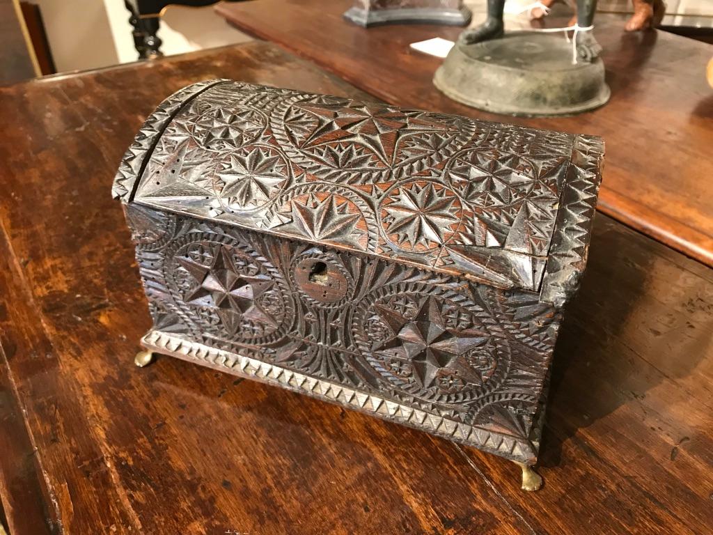 A Spanish late Baroque walnut dome topped box with exquisite chip carving covering the surface, on brass paw feet. The detailed geometric carving is of the highest quality, with pinwheels, stars within circles and triangular designs throughout.