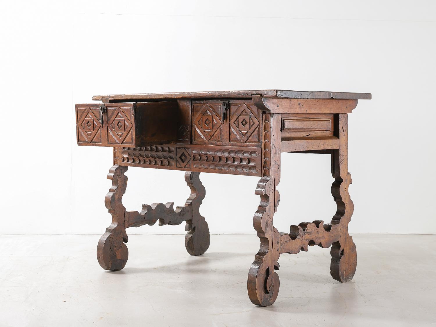 A Spanish 18th century walnut table with decorative original carved frieze with double drawers, original iron pulls and beautiful lyre legs.
