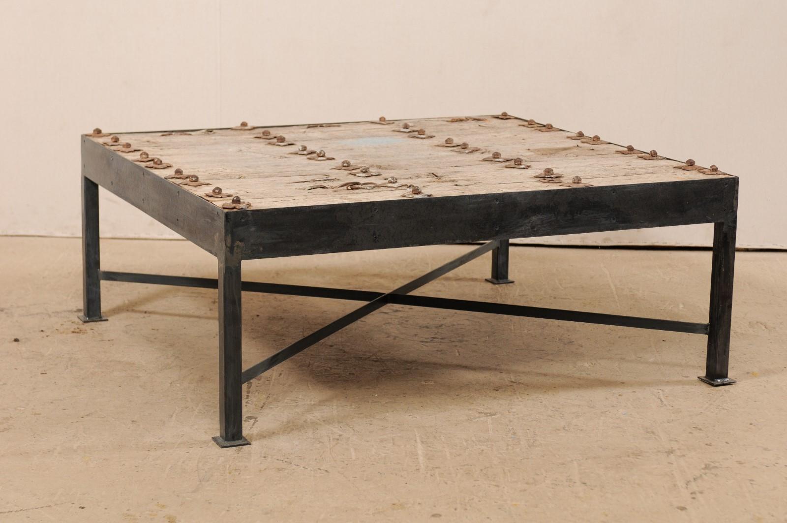 This is a custom coffee table made from an 18th century Spanish door. This wonderful coffee table has been fashioned from an 18th century Spanish door, featuring a wood plank top, with beautifully weathered patina, which is adorn in rows with it's