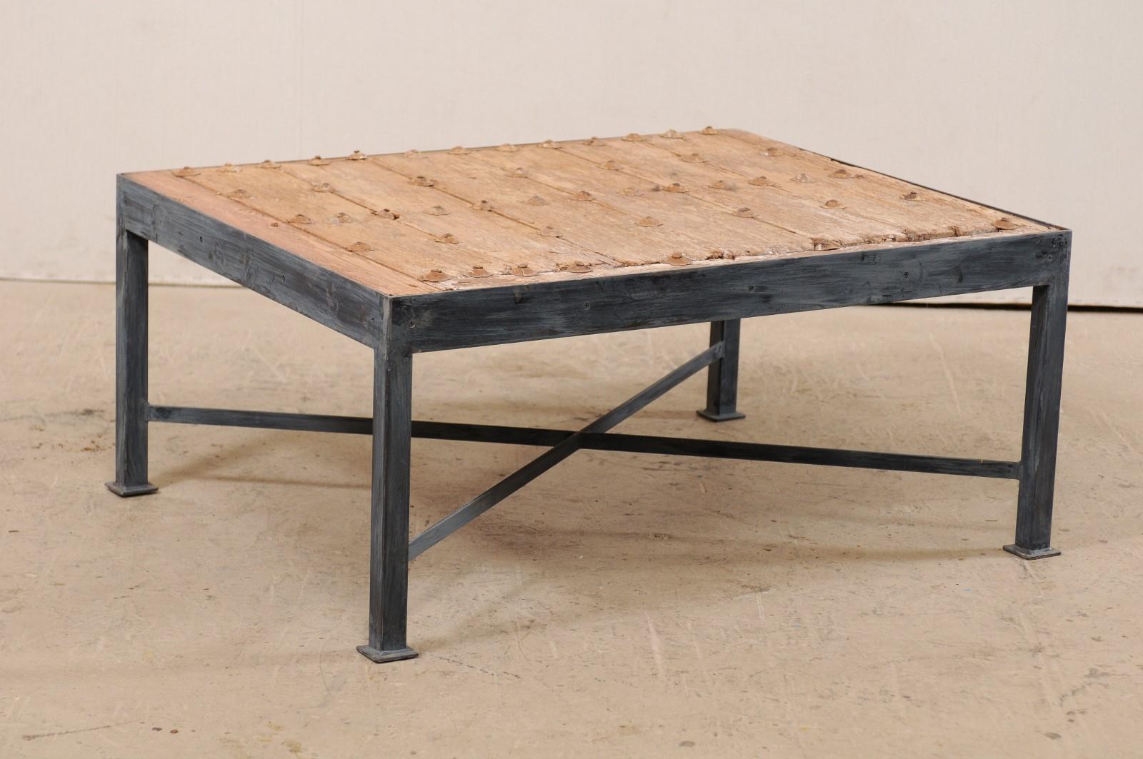 This is a custom coffee table made from an 18th century Spanish door. This wonderful coffee table has been fashioned from an 18th century Spanish door, featuring a wood plank top, with beautifully weathered patina, which is adorn in rows with its
