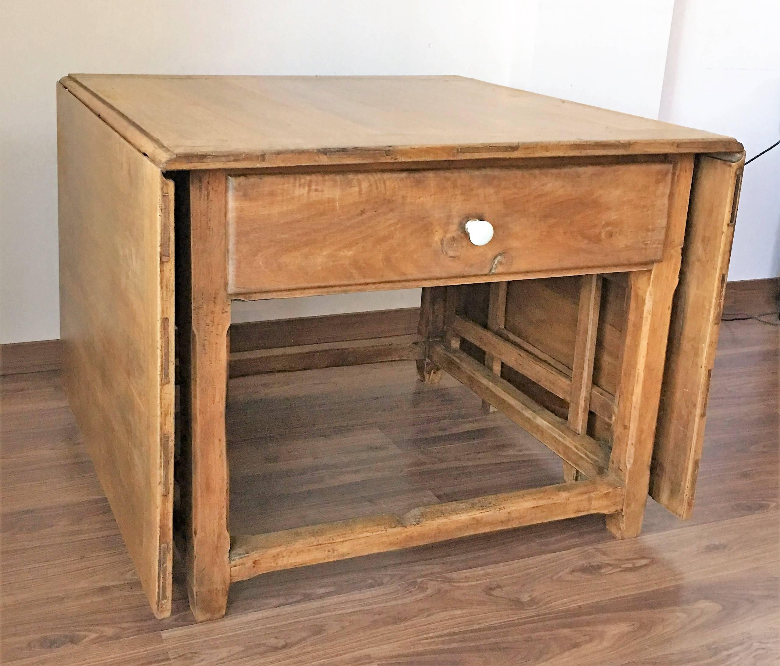 Table à abattant avec pieds de porte. Cette table de style fermier rustique espagnol du 18e siècle comporte deux feuilles mobiles, des pieds en forme de grille et trois tiroirs avec leur tirette originale en céramique.
Le bois, c'est du noyer