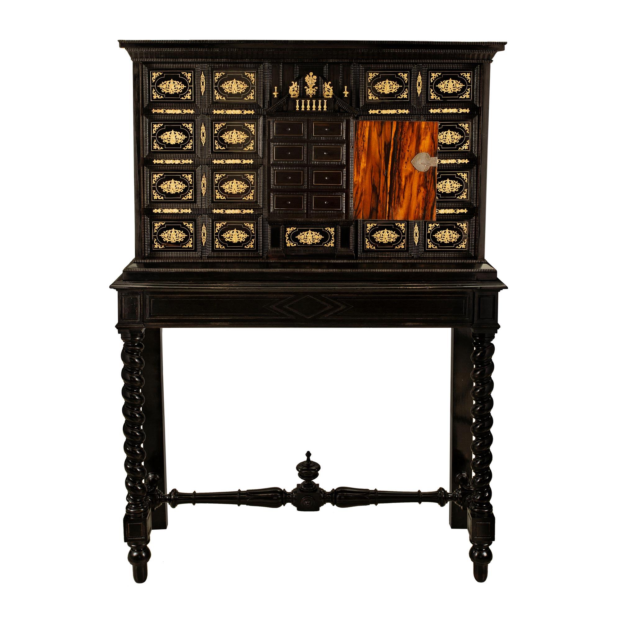 A stunning early 18th century Spanish ebonized fruitwood, rosewood, bone and ormolu specimen cabinet. The cabinet is raised on its original base with beautiful spiral legs and block reserves with topie shaped feet. Each leg is connected by a most