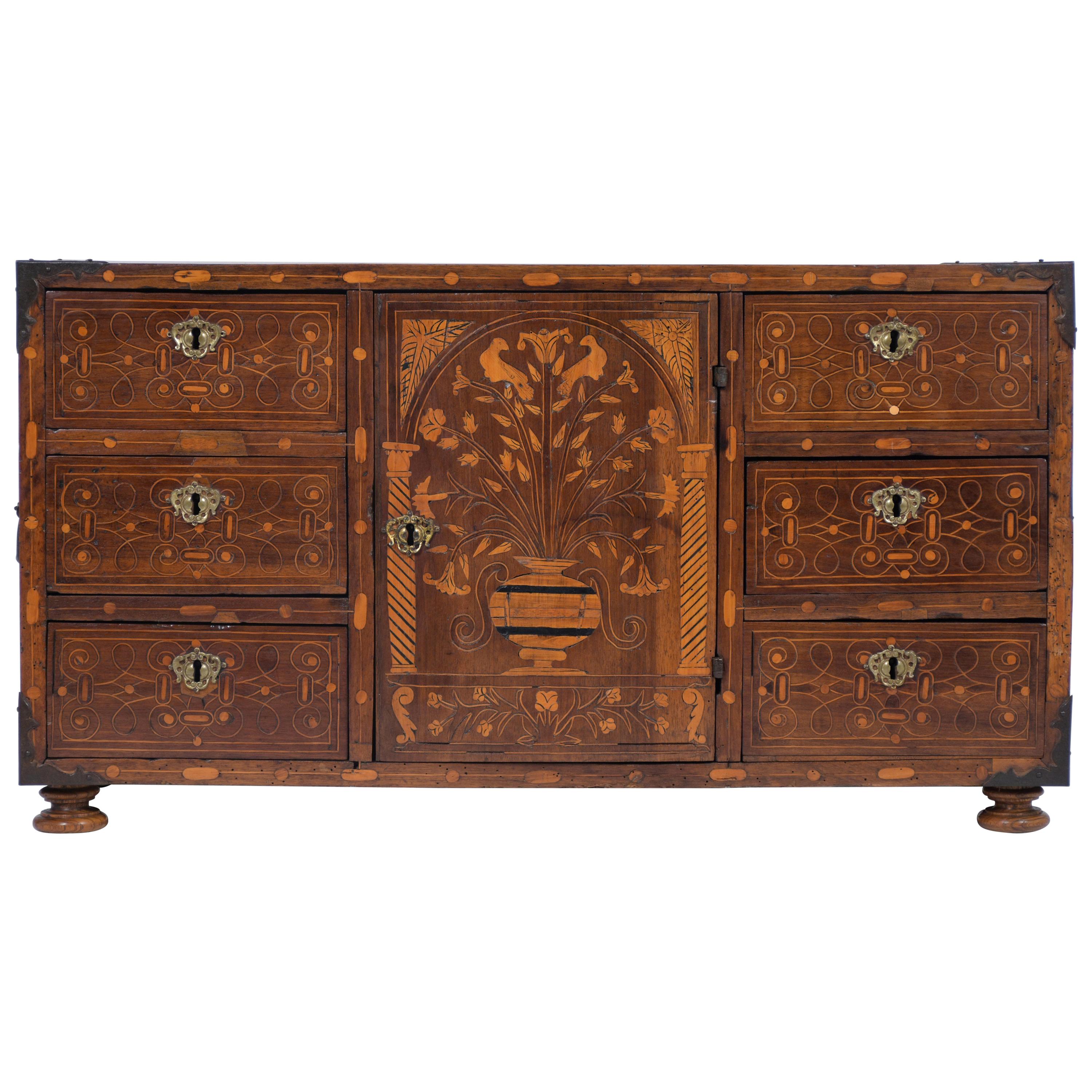 This exquisite 18th-century Spanish Baroque cabinet has marquetry inlays along the front and sides and is stained in a rich walnut color with a waxed patina finish. The jewelry box has wrought iron details, six drawers adorned with their original