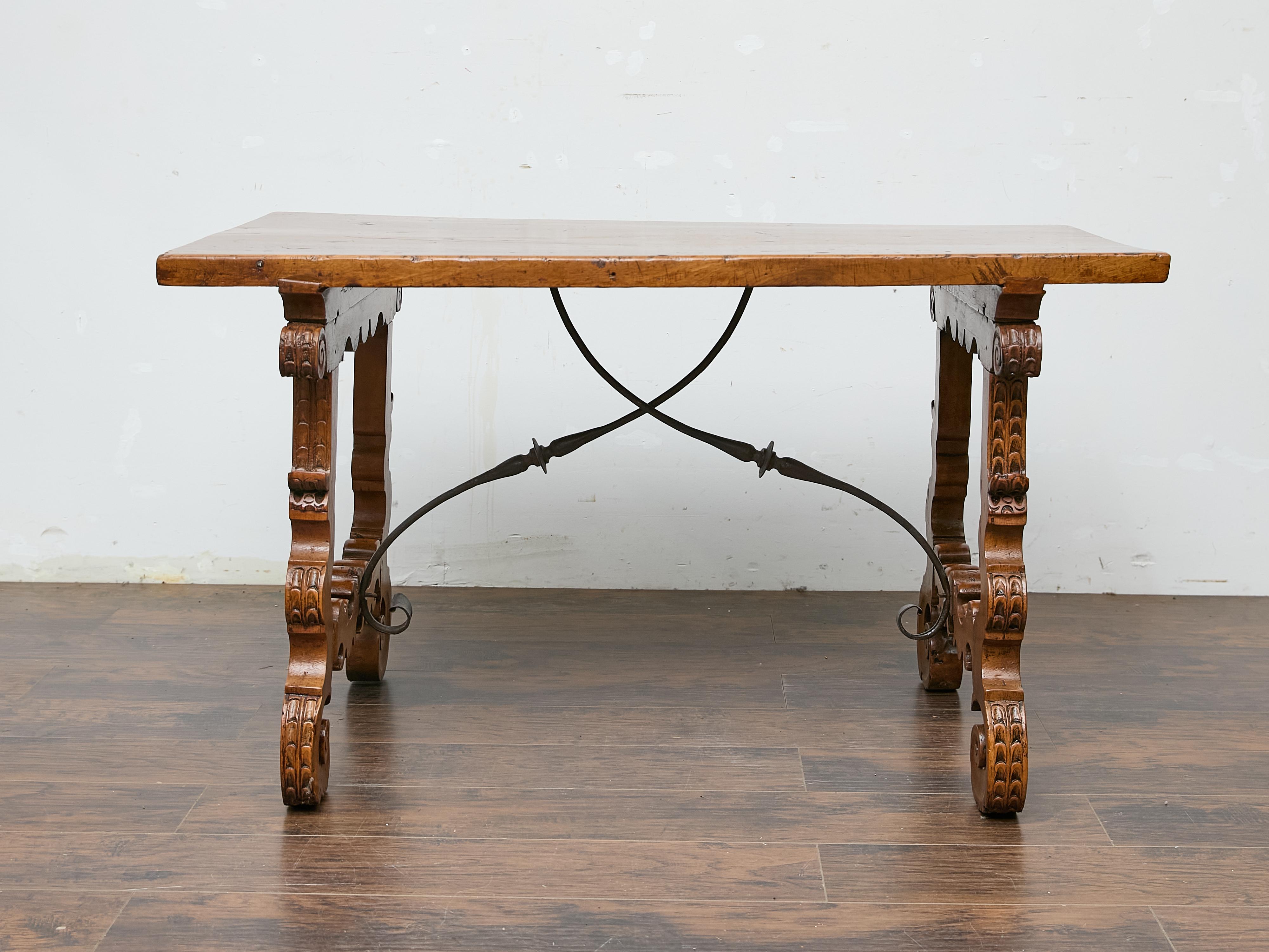 A Baroque style walnut Fratino table from the 18th century with wrought-iron stretchers. A striking example of Spanish Baroque craftsmanship, this 18th-century walnut Fratino table captivates with its sculptural presence and rich patina. The