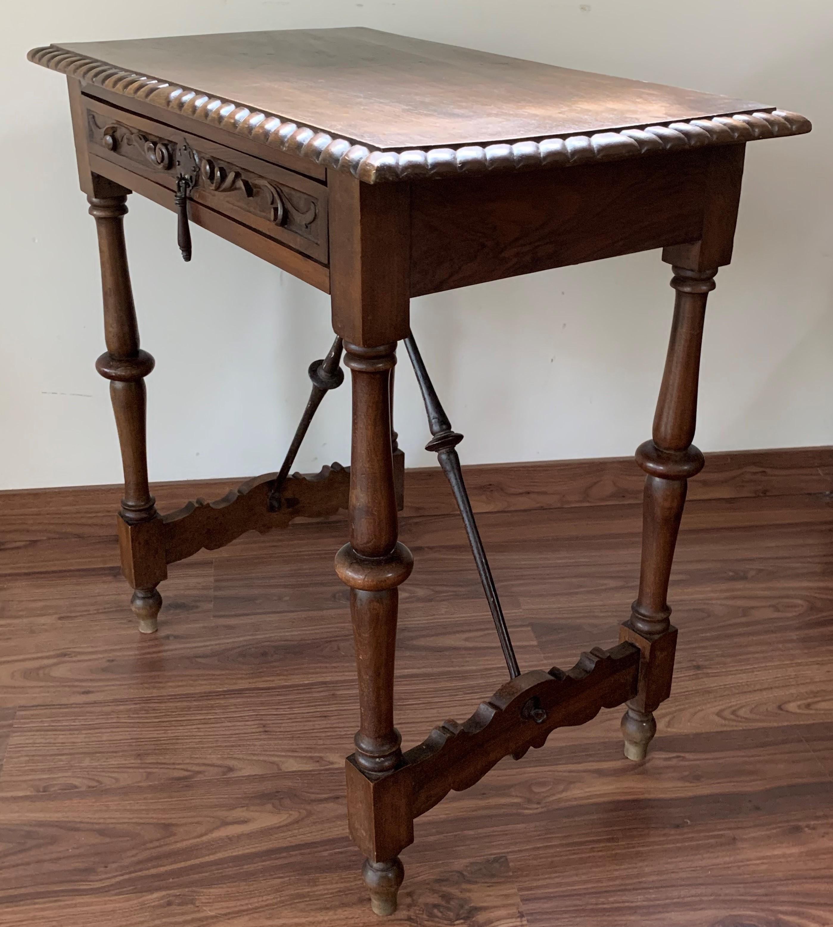 A Spanish walnut side table with single drawer, scalloped apron and carved legs from the late 19th-early 20th century. This elegant Spanish table features a simple, rectangular top with carved edges sitting above a drawer. The table is raised on an