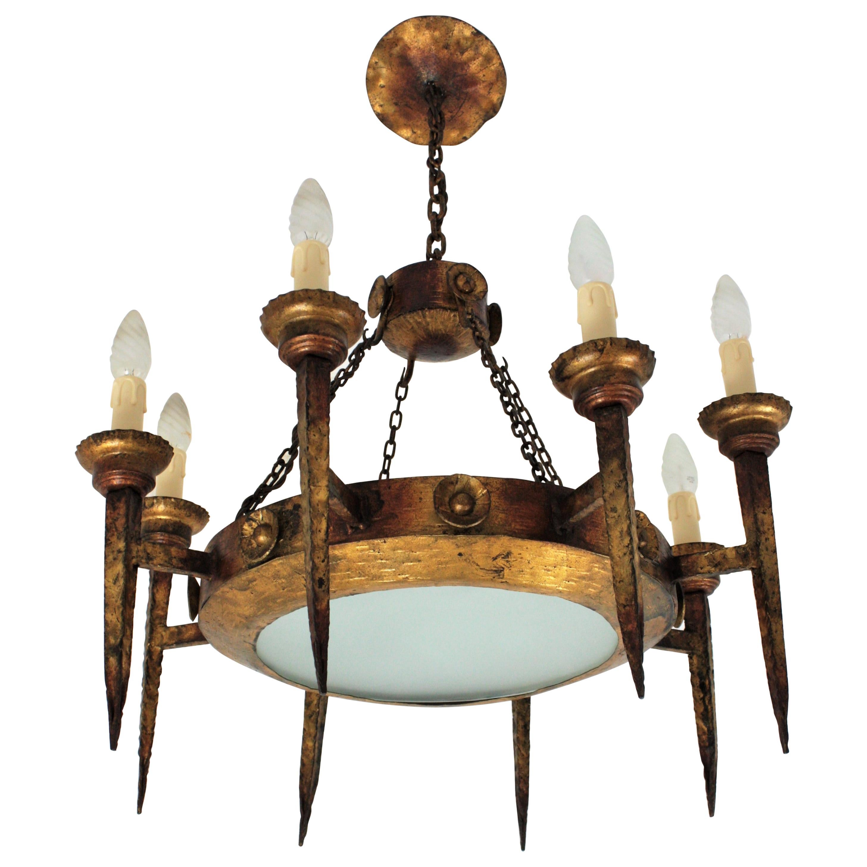 Ring Chandelier with Eight Torch Lights, Wrought Iron, Spain, 1930s
Outstanding large wrought gilt iron ring chandelier with 8 torch arms and central glass light diffuser. 
This spanish early 20th century torchere chandelier features a central iron