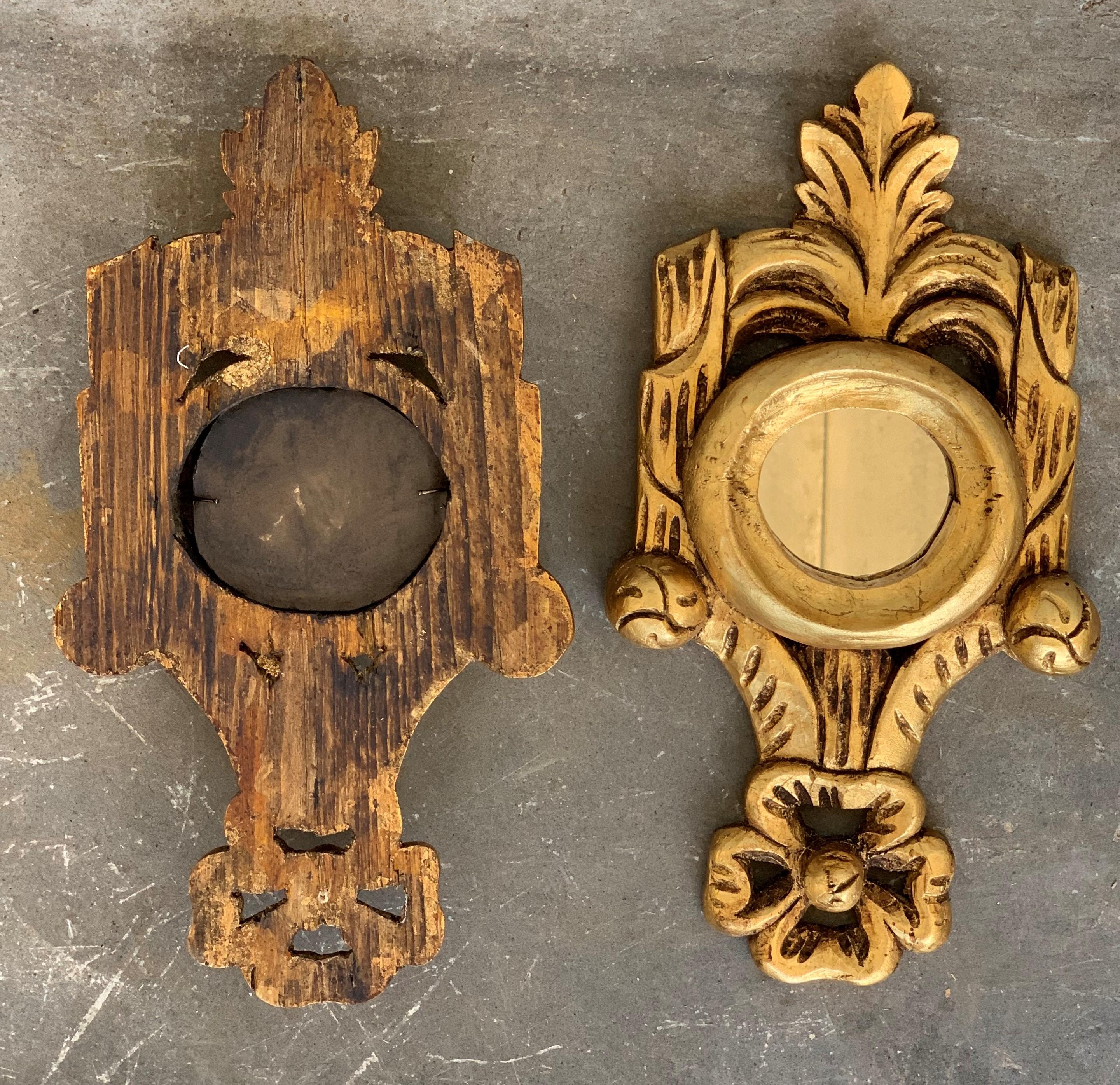 Exquisite Rococo style miniature carved mirrors with a crest on the top and carved naturalistic details at the frames. These pieces are unusual due to their size, they wear their original glasses and they are made of carved wood, gesso and 24-karat